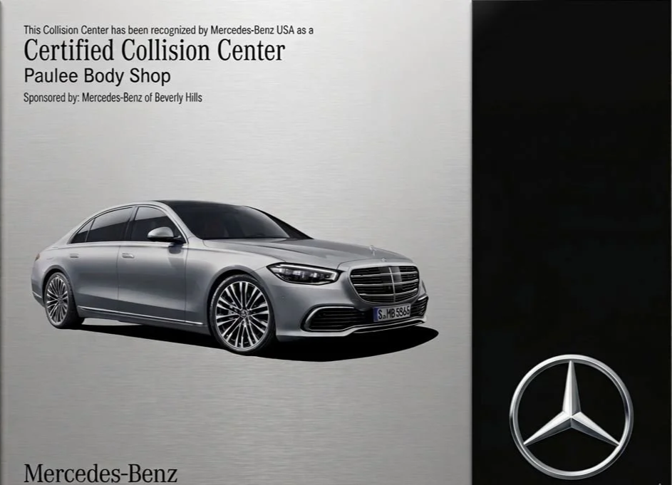 A poster displaying a silver Mercedes-Benz sedan, with text indicating the car is recognized as a Certified Collision Center at Paulee Body Shop, sponsored by Mercedes-Benz of Beverly Hills. The Mercedes-Benz logo is at the bottom right of the poster.