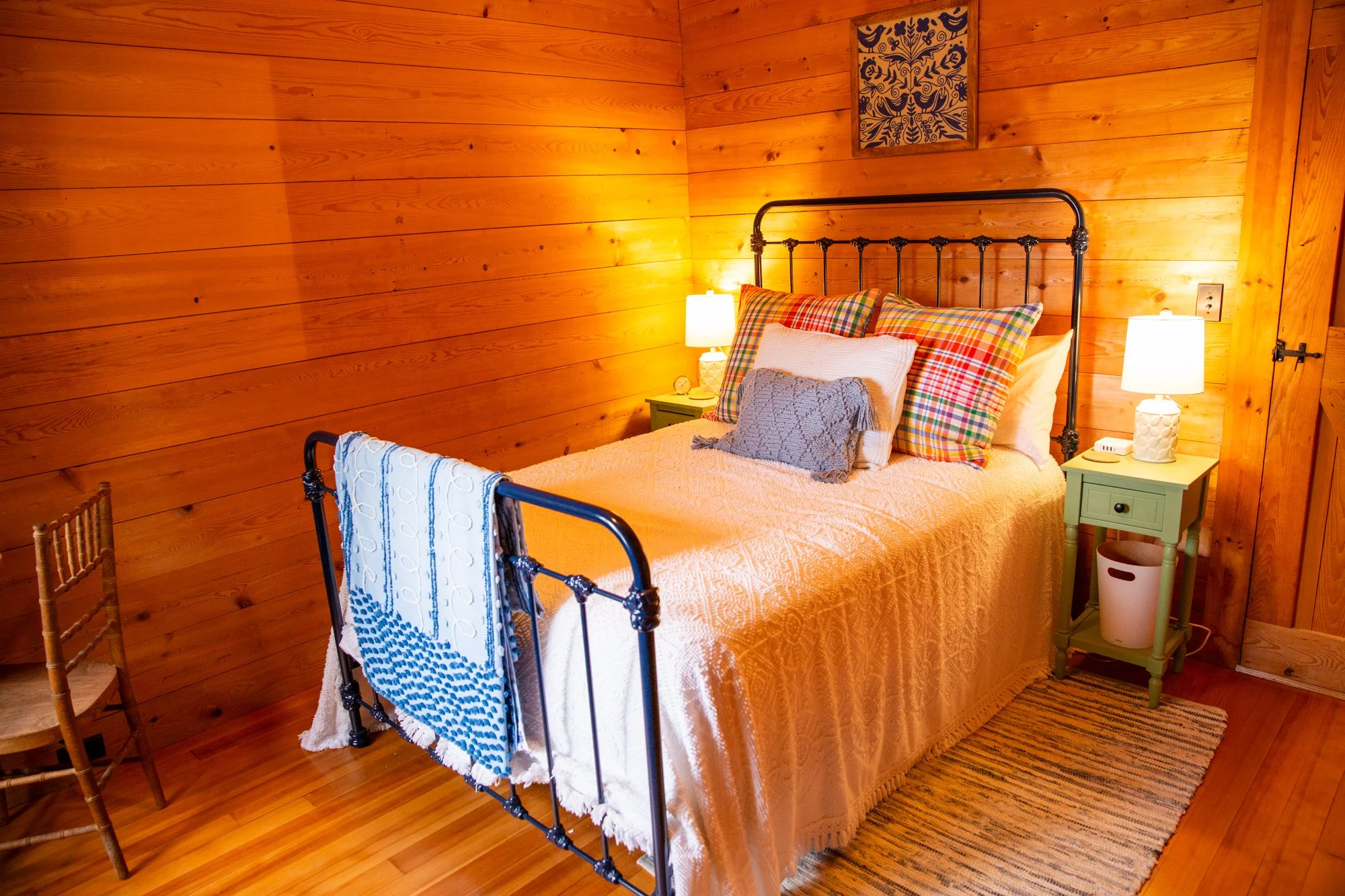 high-head-brooklin-maine-bedroom-iron-bed-plaid-pillows-pine-paneled-walls.jpg
