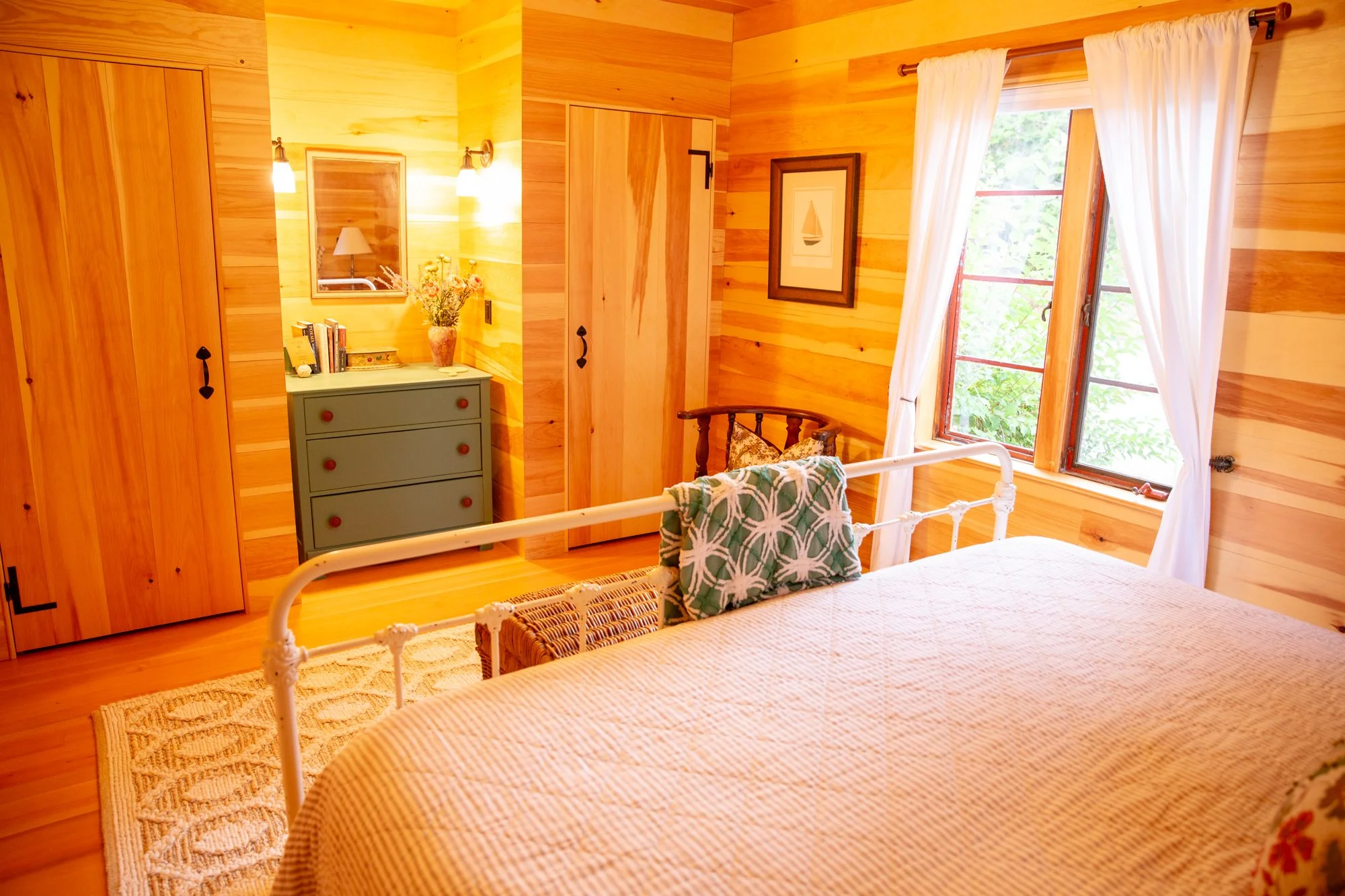 high-head-brooklin-maine-bedroom-iron-bed-wood-paneling-arched-windows-dresser.jpg