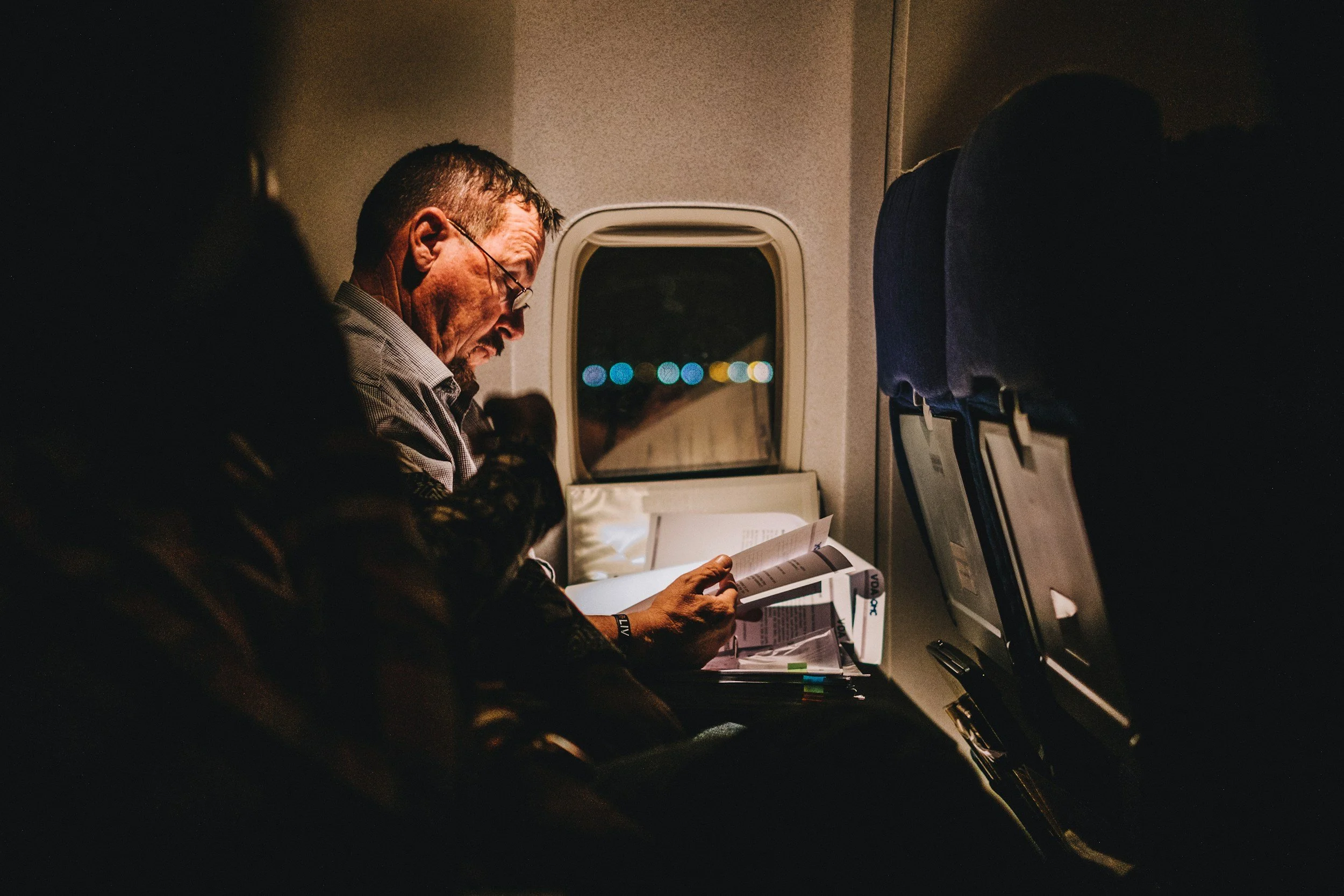 A man sitting in an airplane seat at night. if you travel for work you can still get online therapy with Dr.Irina as she is licensed in Ohio and authorized to practice in over 40 states.  NJ, FL, KY,GA and more