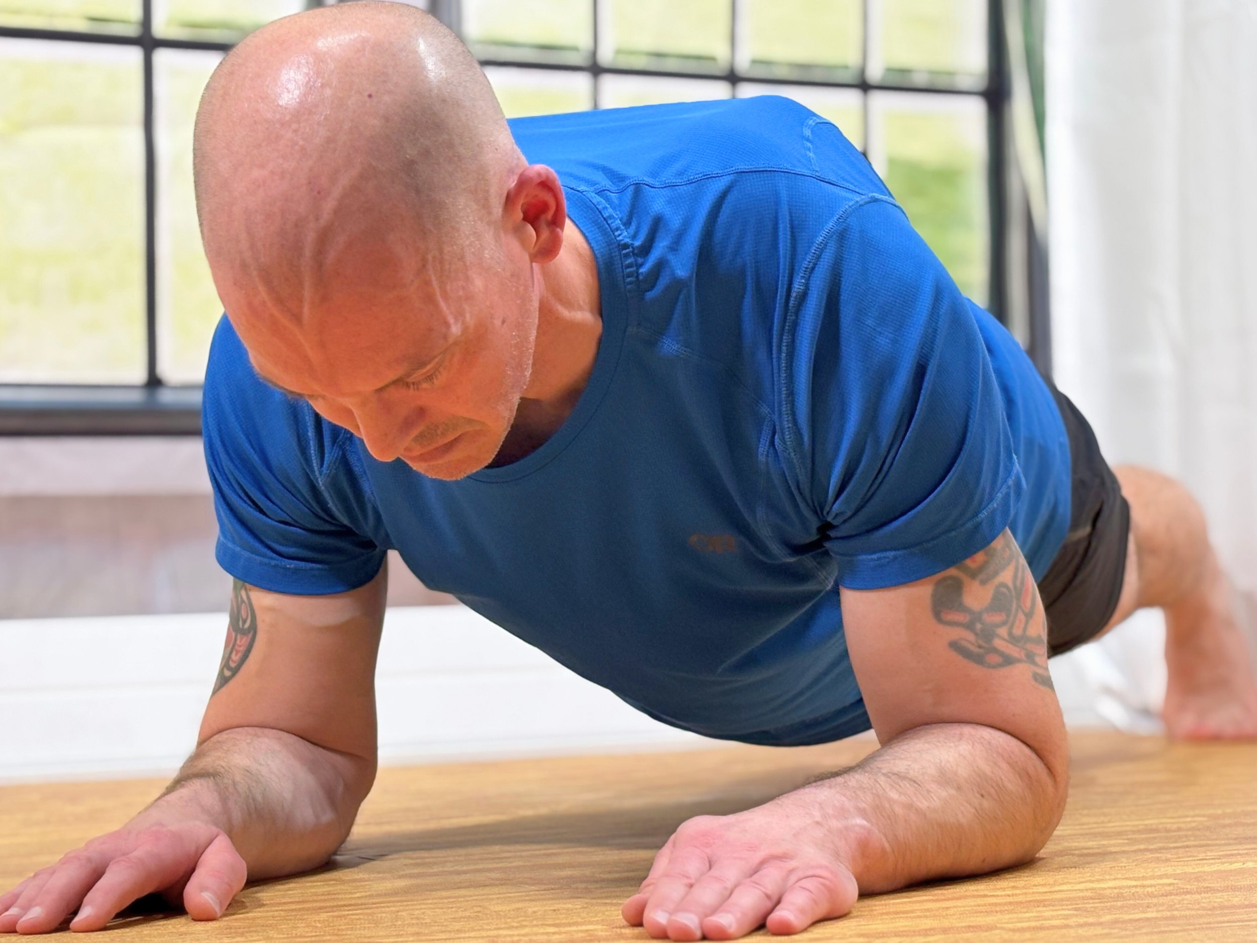 Shane performing a plank exercise for beginners in a live virtual HIIT Pilates session