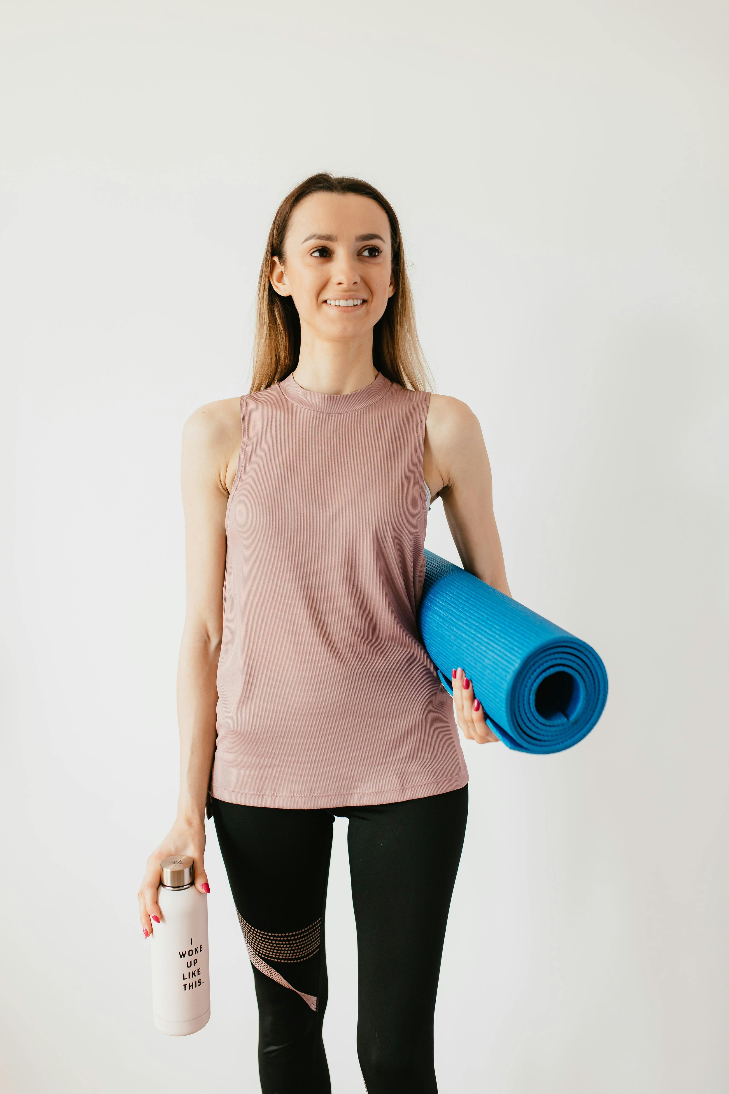 Woman ready for a beginner-friendly HIIT Pilates workout with yoga mat and water bottle