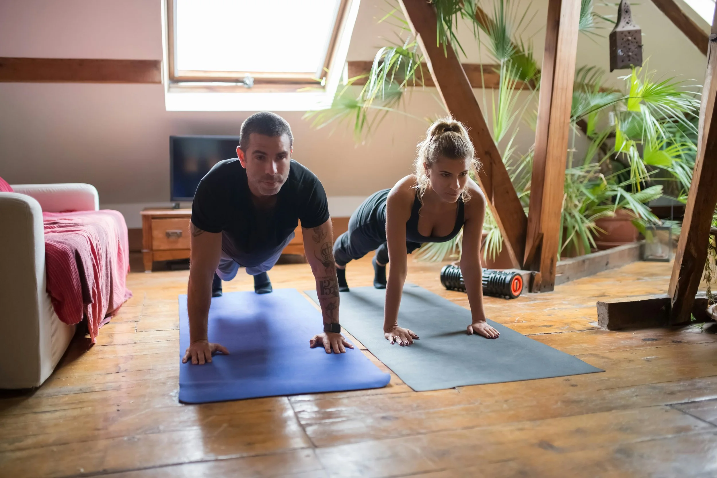 Couple practicing beginner HIIT Pilates exercises together at home