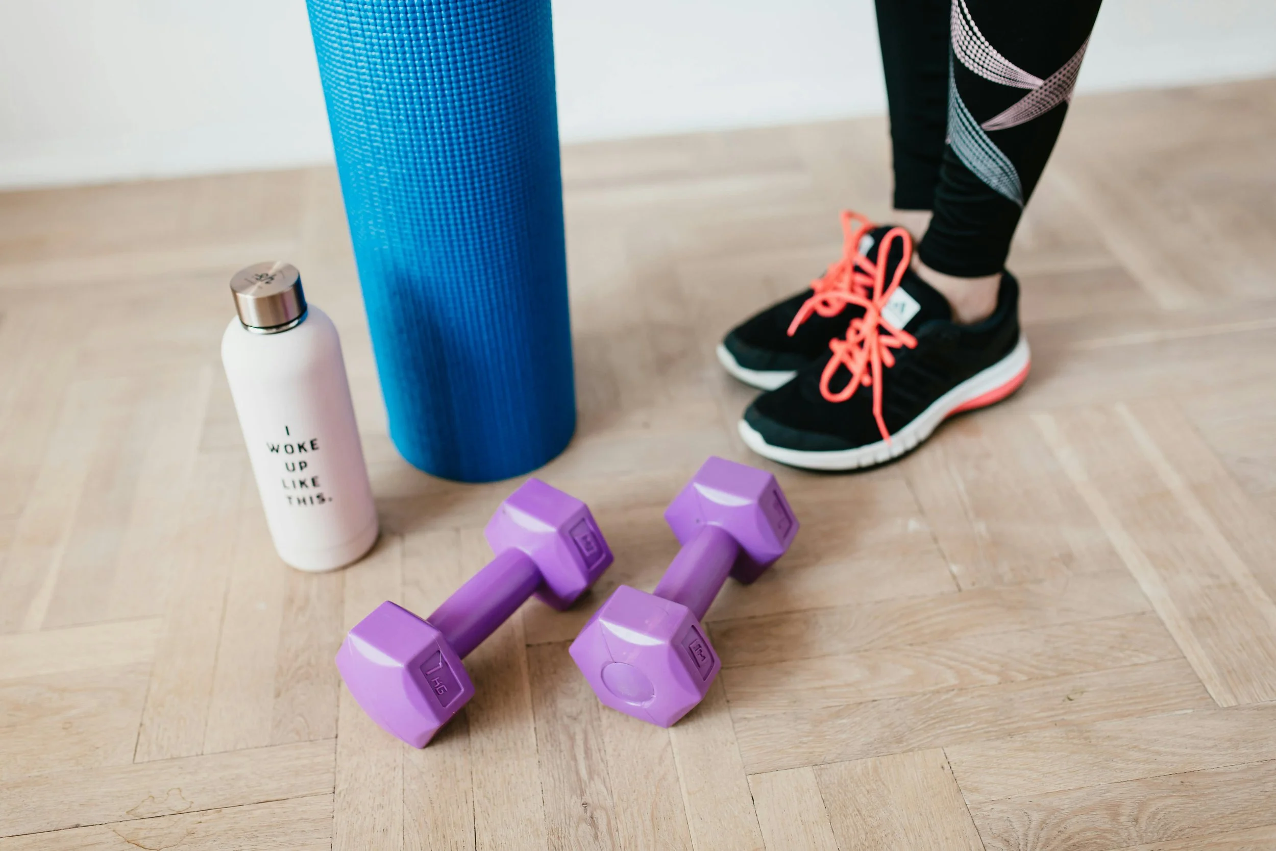 Workout essentials for a beginner HIIT Pilates class - sneakers, yoga mat, dumbbells, and water bottle