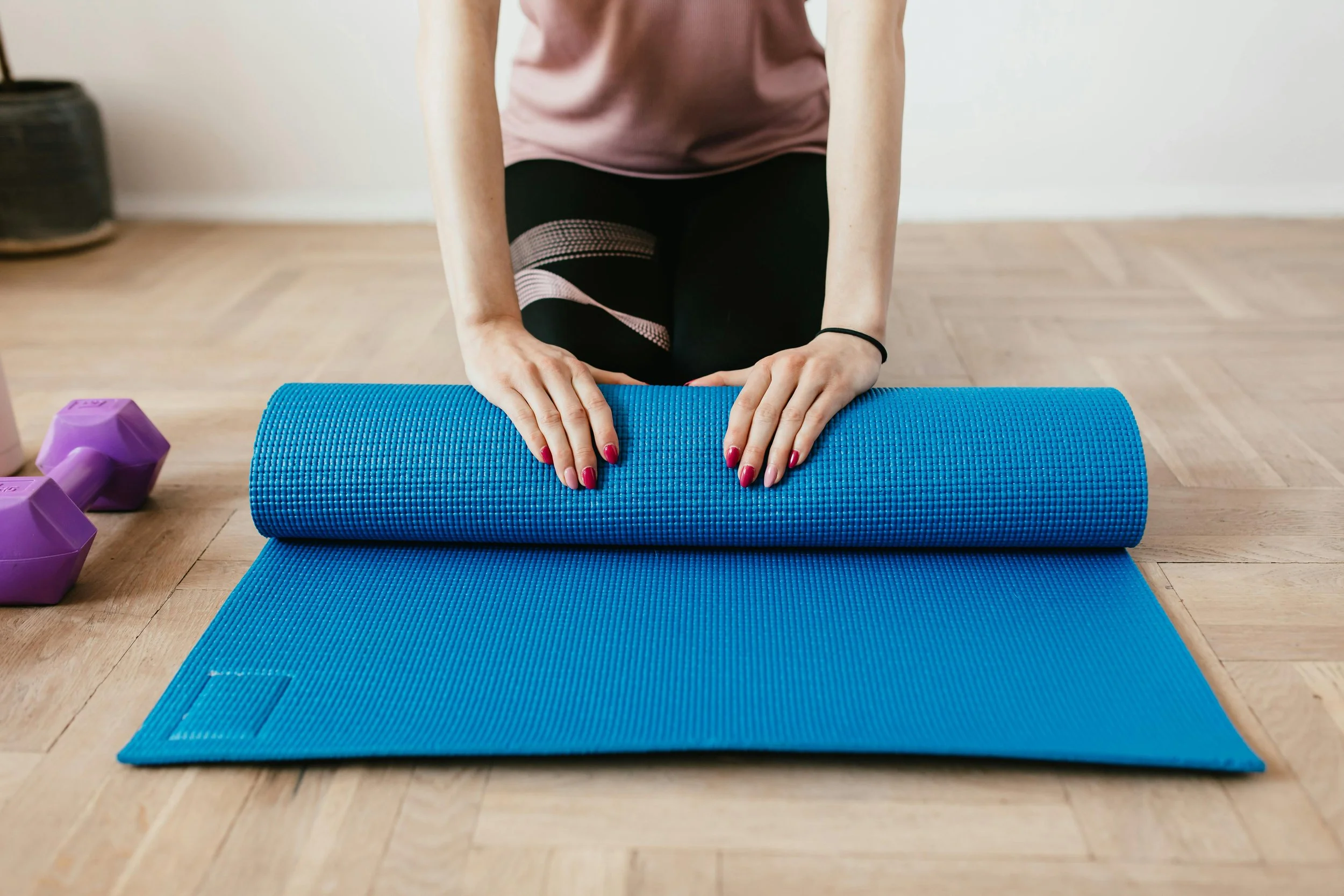 Setting up for a beginner HIIT Pilates class at home with yoga mat and dumbbells