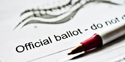 Close-up of a printed ballot with the words 'Official ballot' and a red pen resting on it.