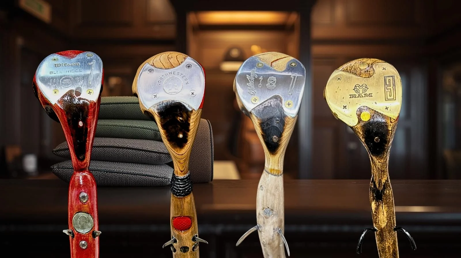 Four golf clubs with different head designs and colors, standing upright on a surface in front of a dark wooden background.