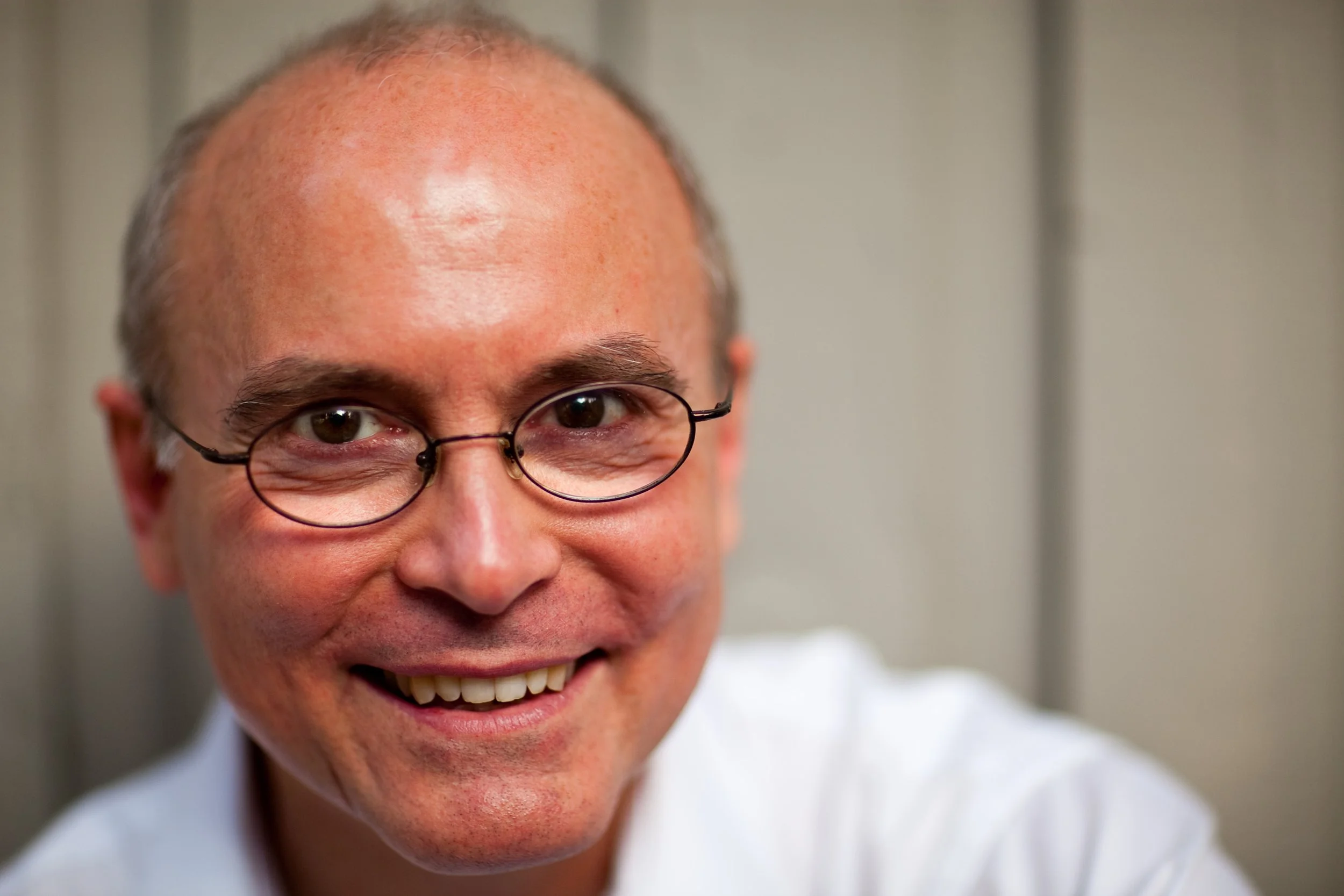 A middle-aged white man with oval glasses, smiling