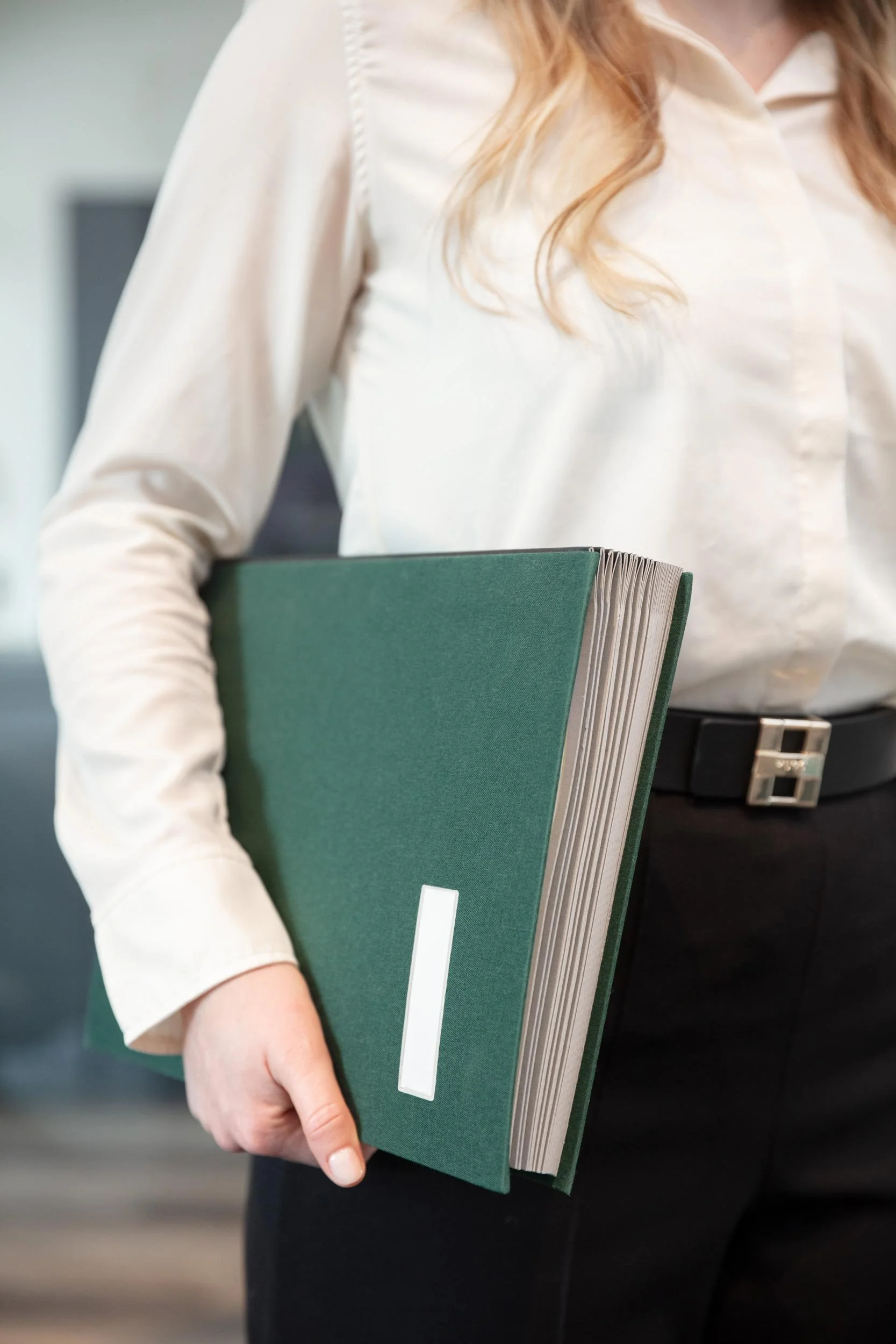 Eine Mitarbeiterin von Regina Lackner trägt einen Ordner unter dem Arm.