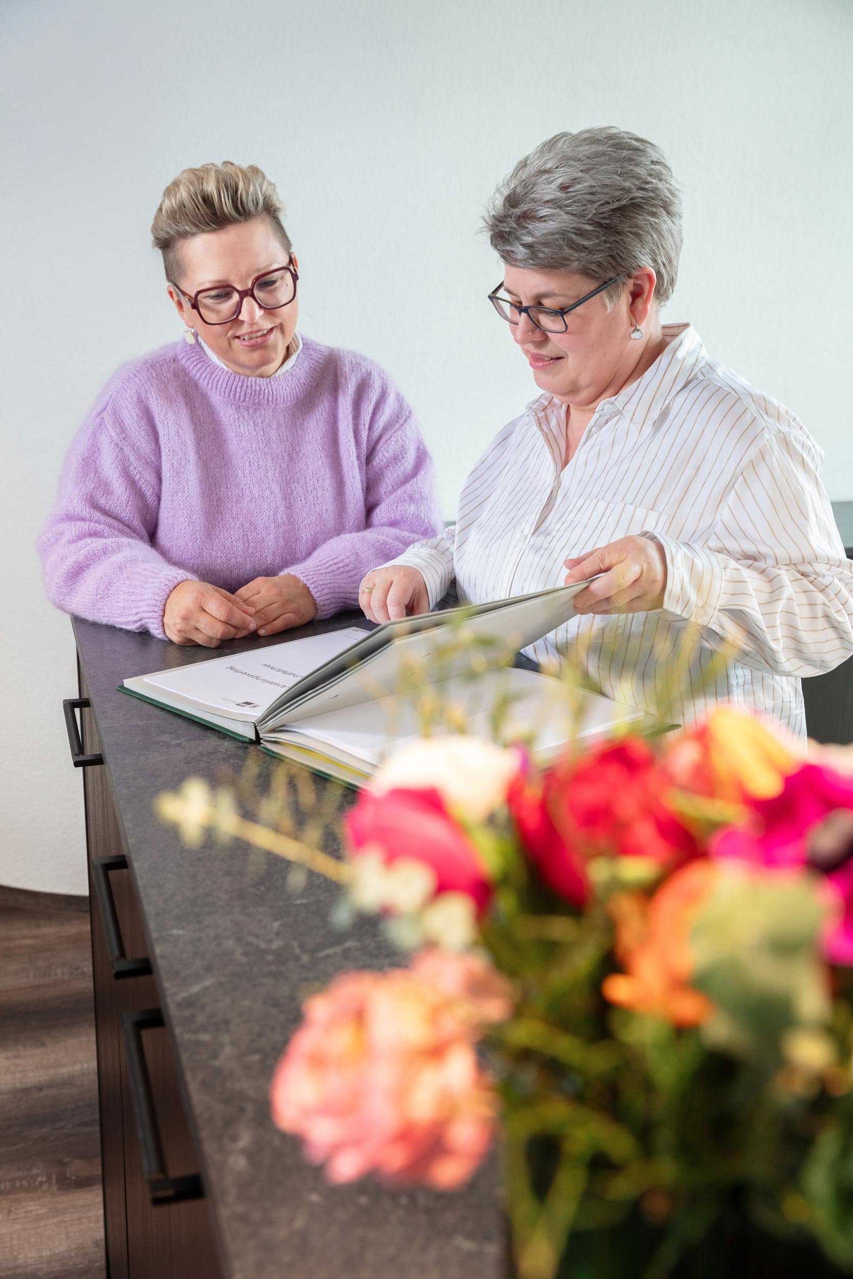 Regina Lackner an der Empfangstheke im Gespräch mit der Sekretärin Christine Weese