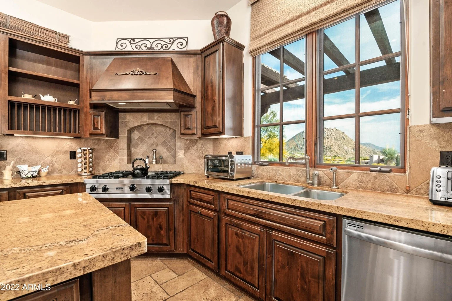 Kitchen with wooden cabinets, a large window overlooking a desert landscape, and a granite countertop.