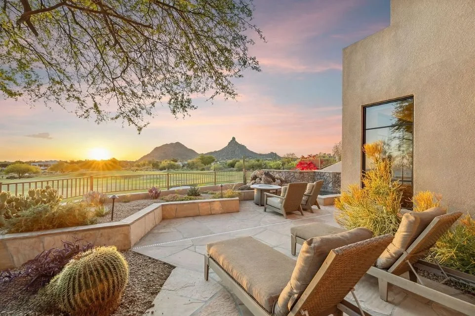 Luxury Scottsdale patio overlooking a golf course with panoramic mountain views, desert landscaping, and outdoor lounge seating at sunset.