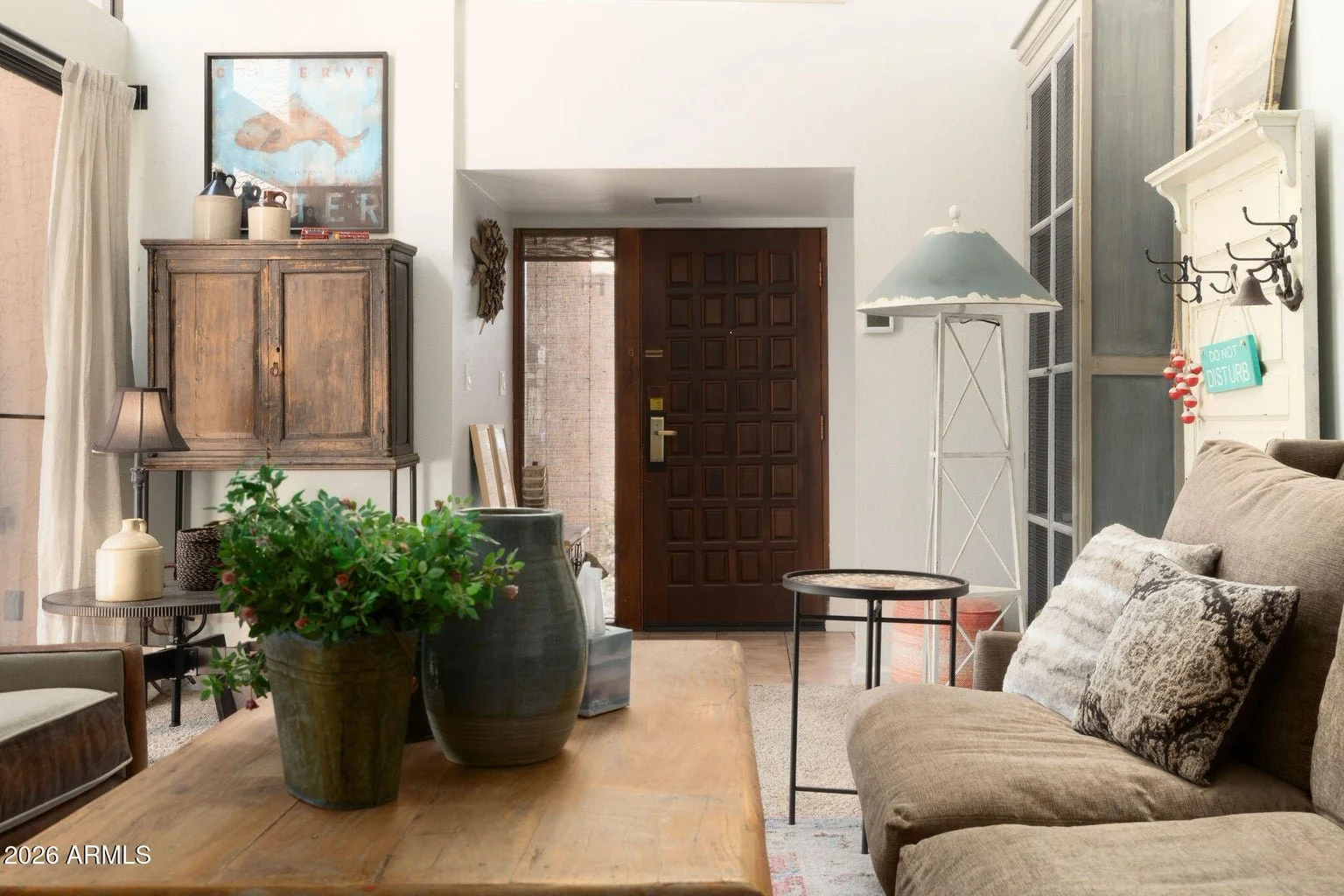 Living room and entryway at The Shores at McCormick Ranch in Scottsdale, featuring a wood front door, neutral furnishings, and rustic wood accents.