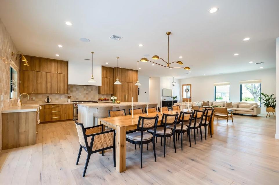An interior dining table and kitchen with warm aesthetic finishes