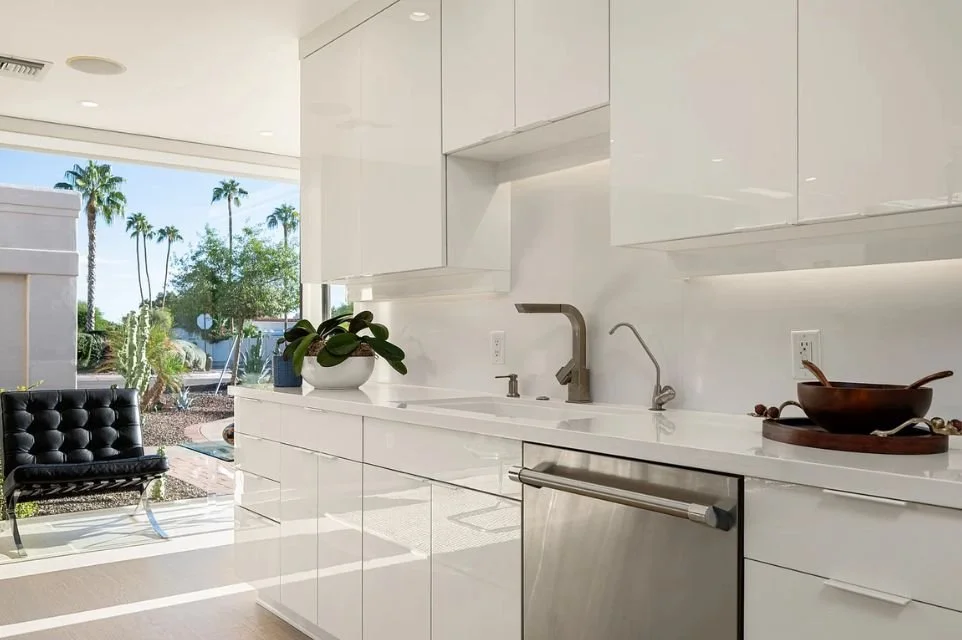 Contemporary white kitchen with sleek cabinetry, stainless steel dishwasher, and desert views in a Phoenix, Arizona luxury home.