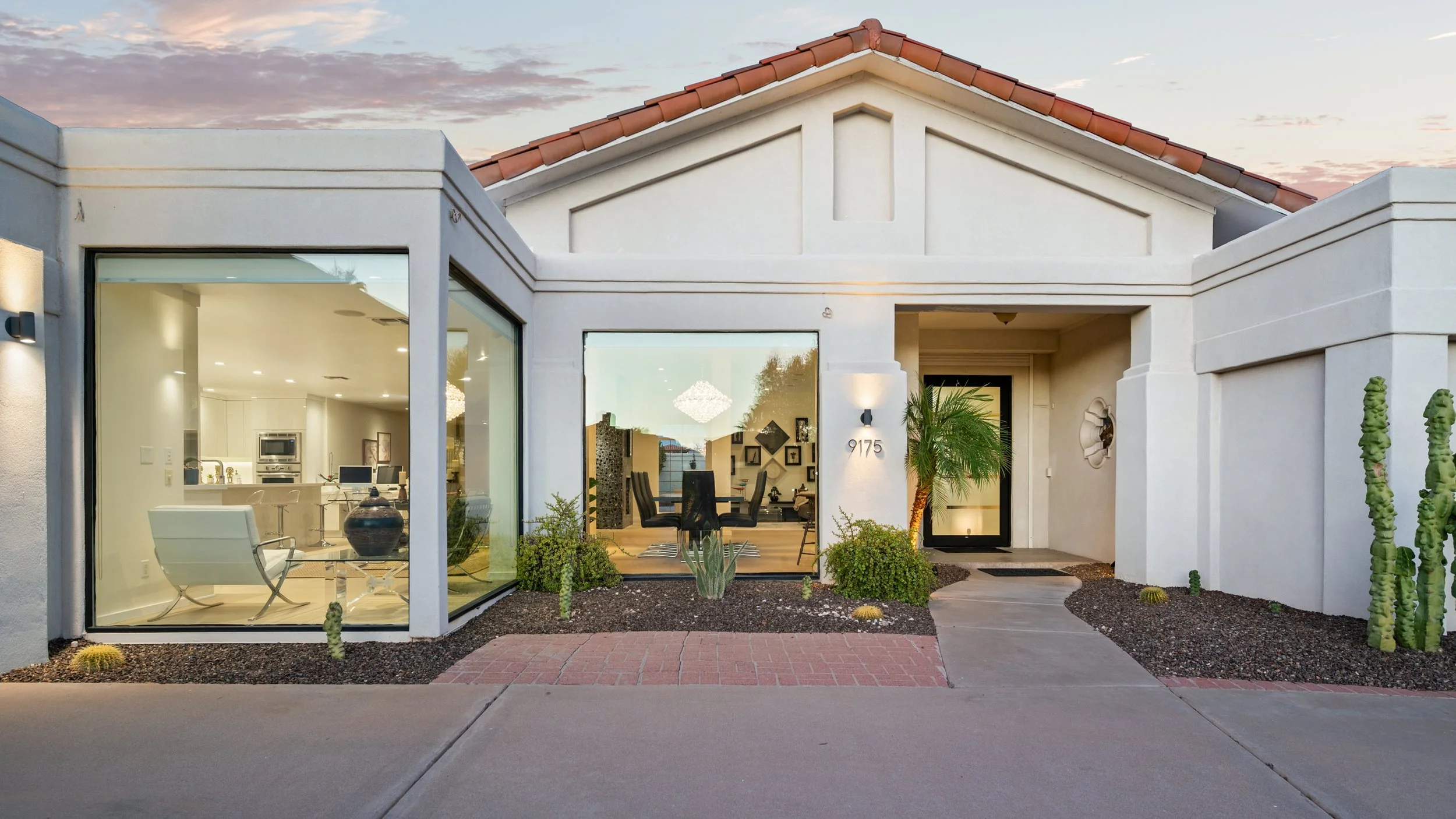 Contemporary home exterior with floor to ceiling glass windows and desert landscaping
