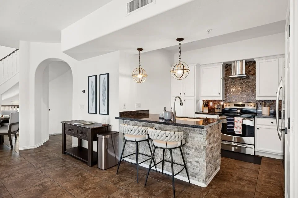 Updated kitchen at 3935 E Rough Rider Road in Phoenix featuring granite countertops, white cabinetry, stainless steel appliances, breakfast bar, and open-concept layout.