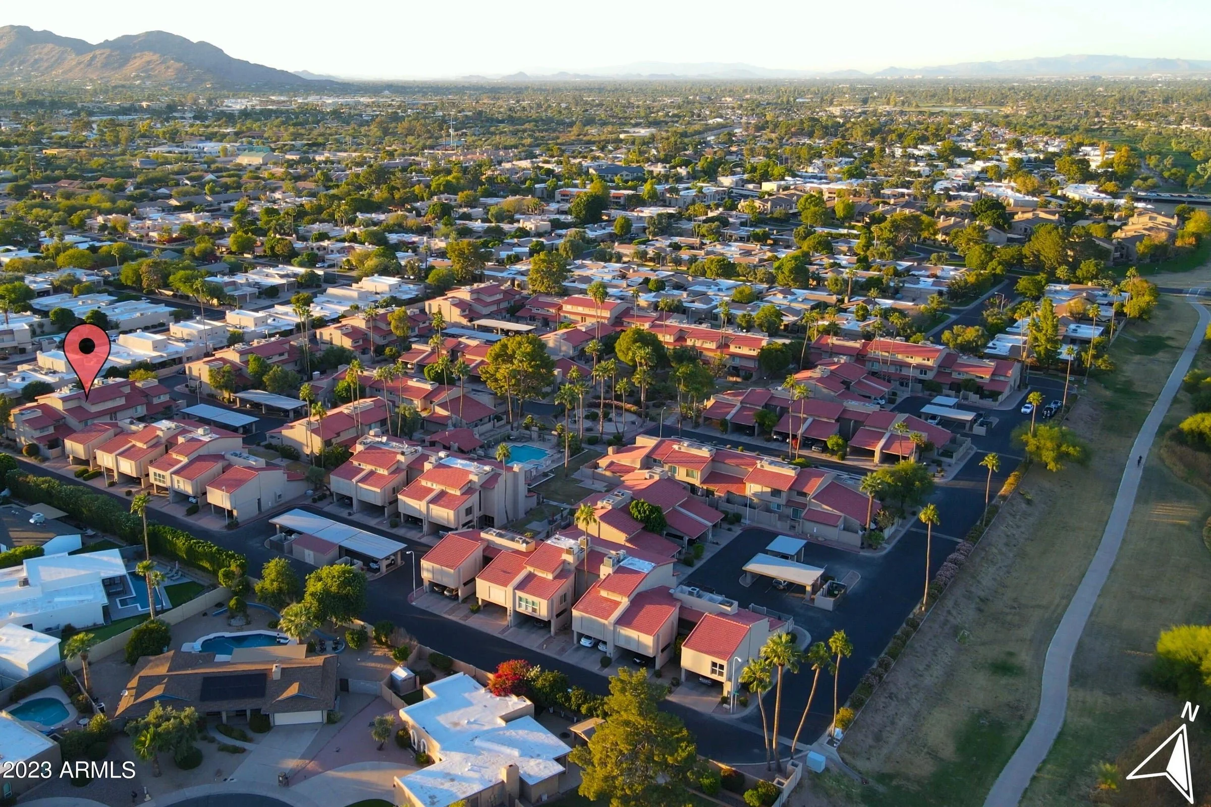 Aerial view of Casitas Chaparral, a townhome community with red tile roofs and a central pool along the Scottsdale greenbelt, with mountains in the distance