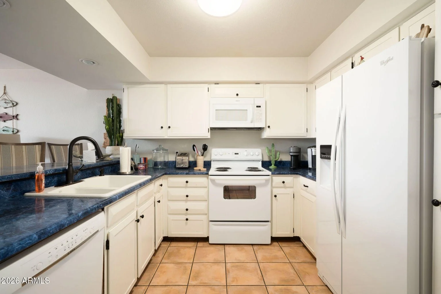 Kitchen at 7401 N Scottsdale Rd #26 in The Shores at McCormick Ranch, Scottsdale, featuring white cabinetry, blue countertops, white appliances, and tile flooring.