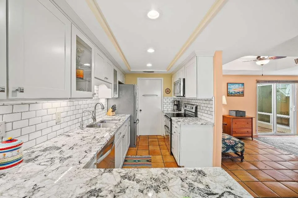 Bright kitchen with marble countertops, subway tile backsplash, and white cabinetry in Scottsdale