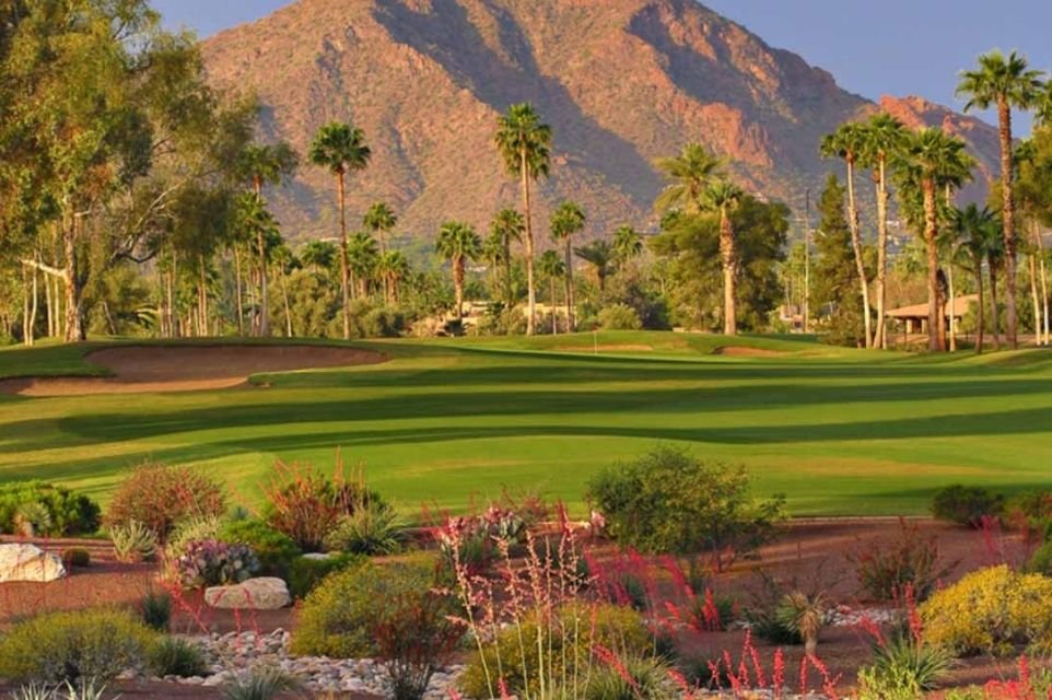 Palm-lined golf course with desert flowers below a red rock mountain in the Scottsdale and Paradise Valley area