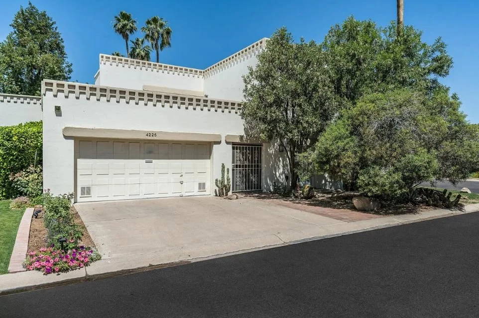 Mediterranean-inspired townhome exterior at Villa d’Este Scottsdale featuring private garage, mature trees, and gated community living.