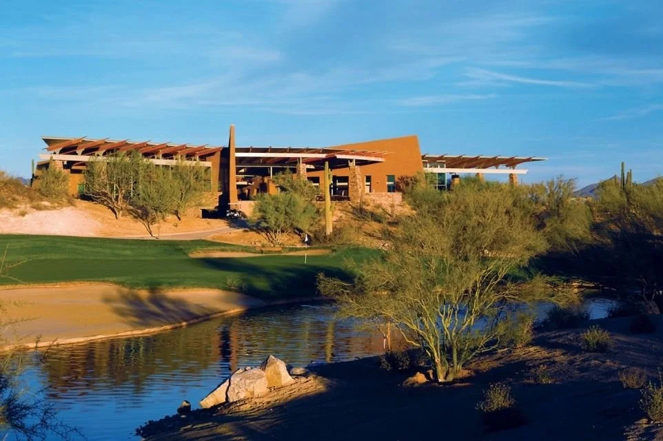 Desert golf clubhouse above a pond and fairway surrounded by Sonoran Desert landscape near Scottsdale