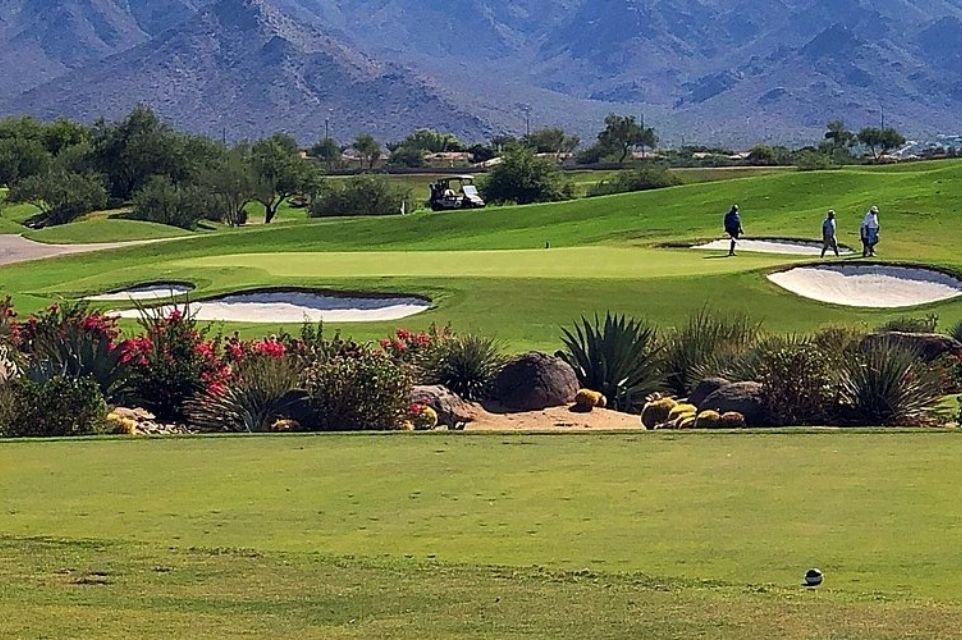 Golfers on a green surrounded by bunkers, desert plants and mountains in the Scottsdale area
