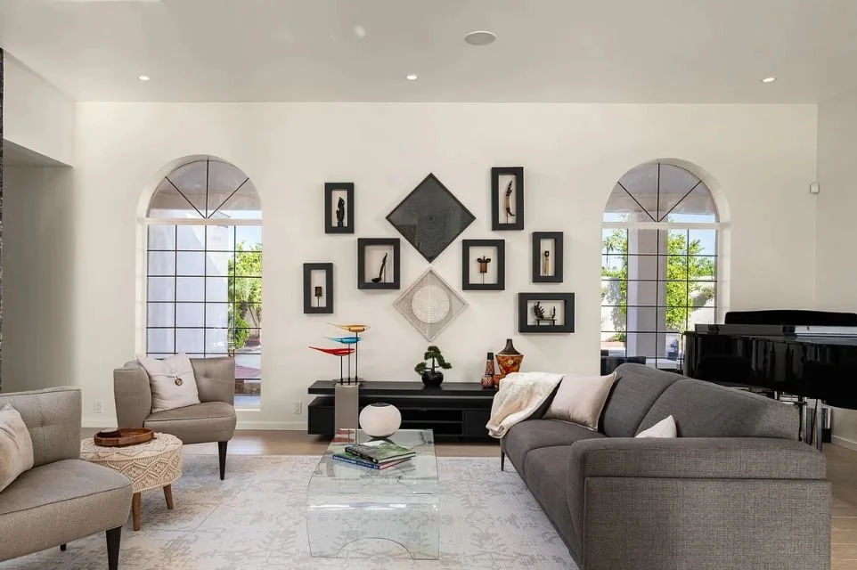 Bright luxury living room with arched windows, contemporary furnishings, artwork, and grand piano in a Scottsdale, Arizona home.