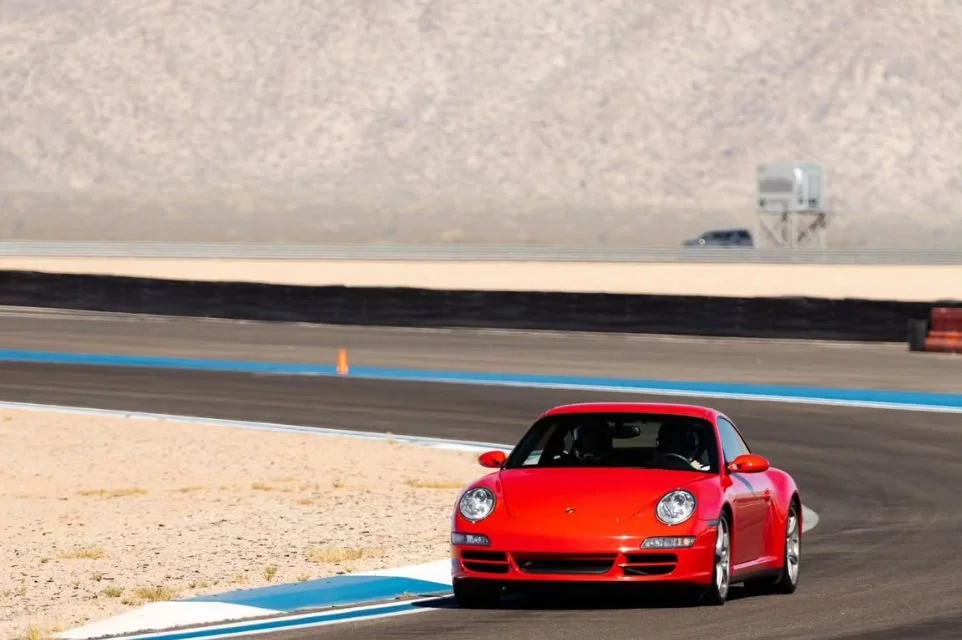 Red Porsche sports car driving on a race track during a high-performance driving experience near Scottsdale, Arizona.
