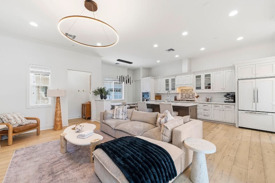 Open-concept luxury living room and gourmet kitchen in Scottsdale featuring custom cabinetry, oversized island, designer lighting, and hardwood floors.