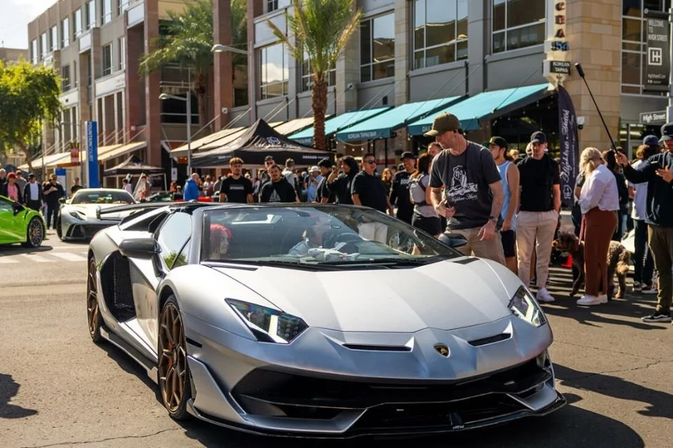 Lamborghini Aventador arriving at High Street Cars & Coffee in North Scottsdale with automotive enthusiasts gathered around.