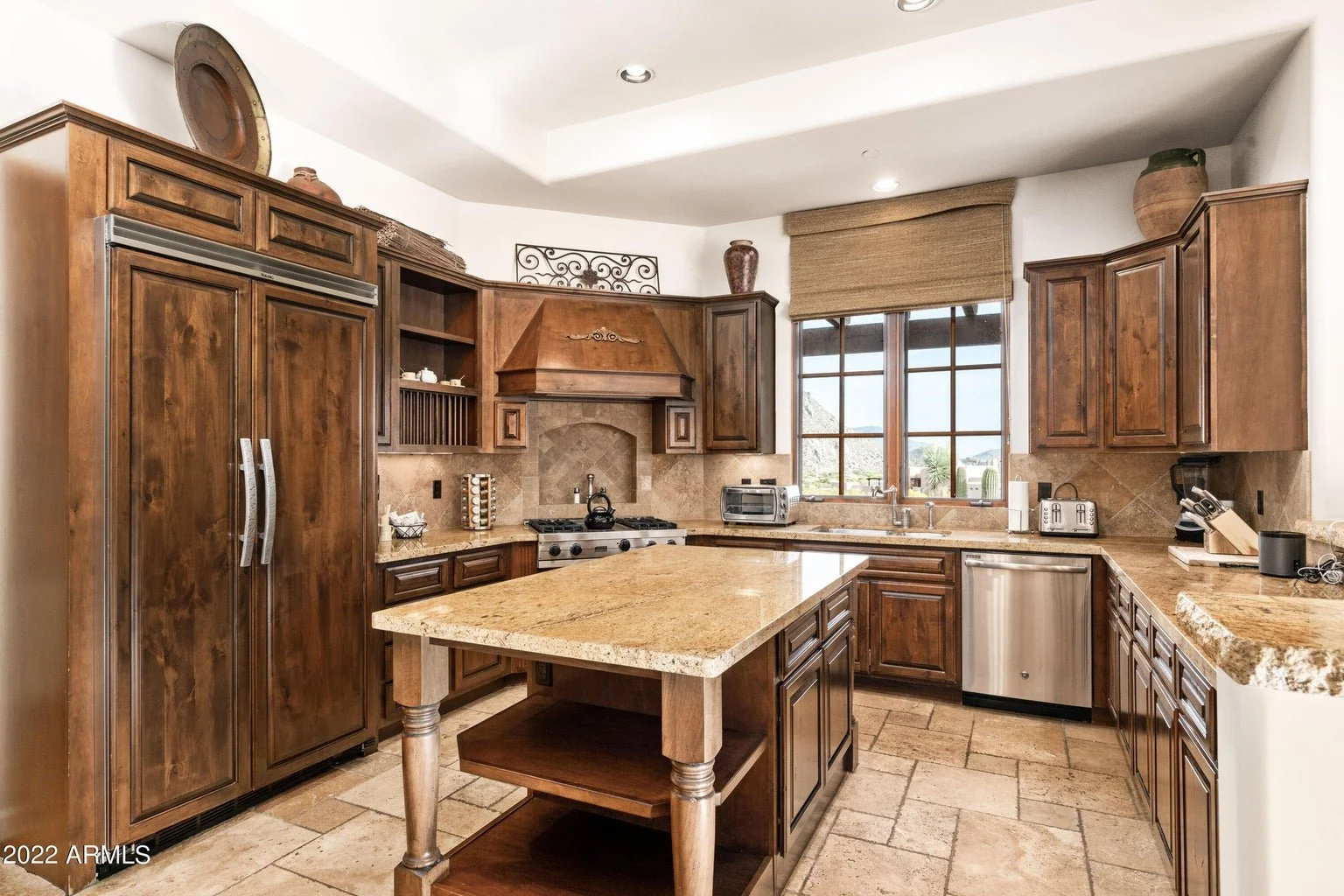 Kitchen with wooden cabinets, granite countertops, a central island, stainless steel appliances, and a large window with a view.