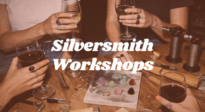 People holding wine glasses around a workshop table with jewelry-making tools and rings, with the text 'Silversmith Workshops' overlayed.