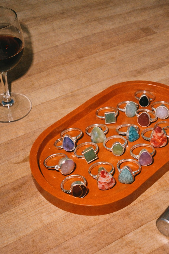 wine and handmade rings in a tray on a table next to a ring mandrel at a silversmith workshop for jewelry making