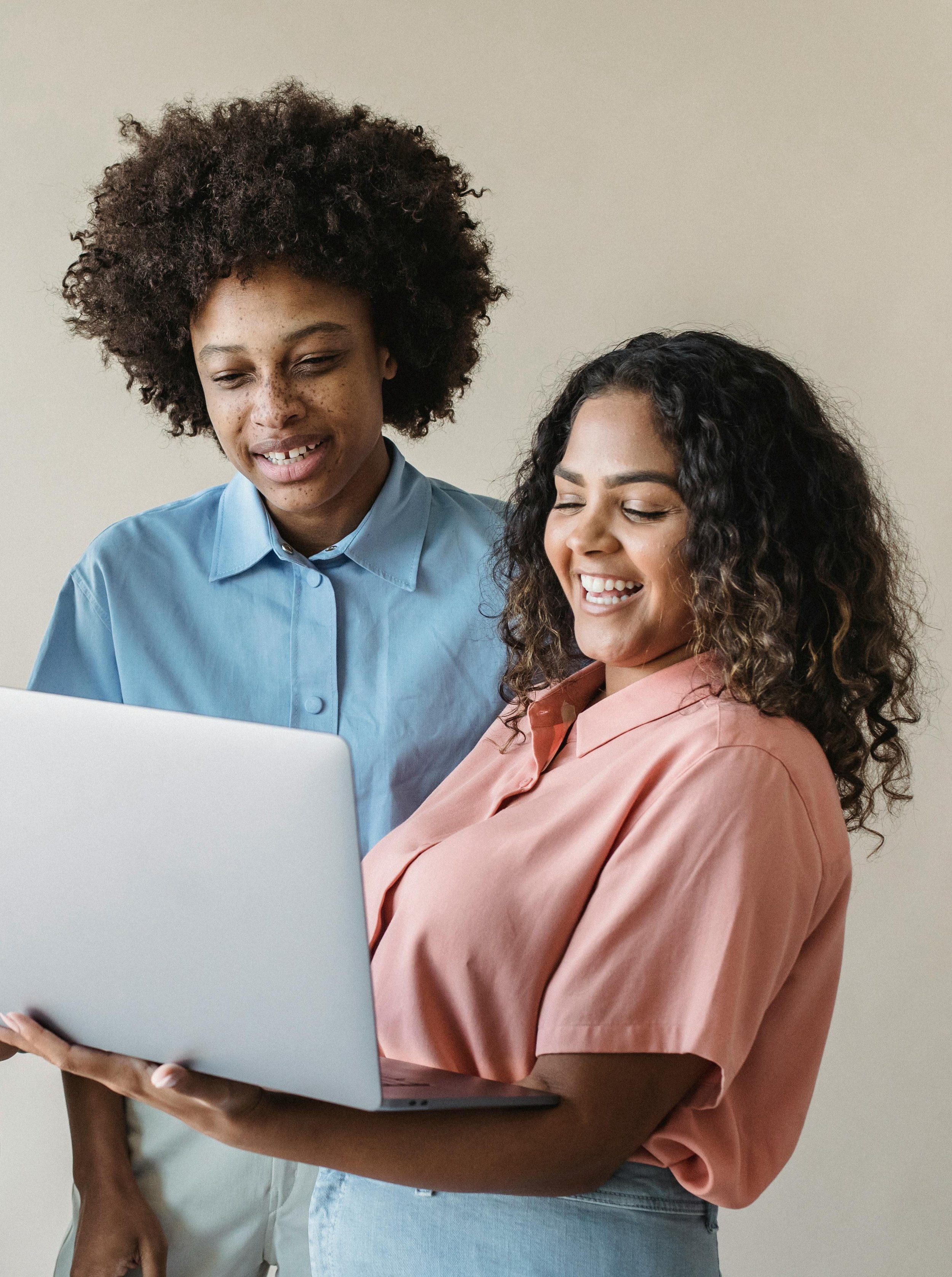 Two women looking at a laptop together, smiling and engaged in a discussion.