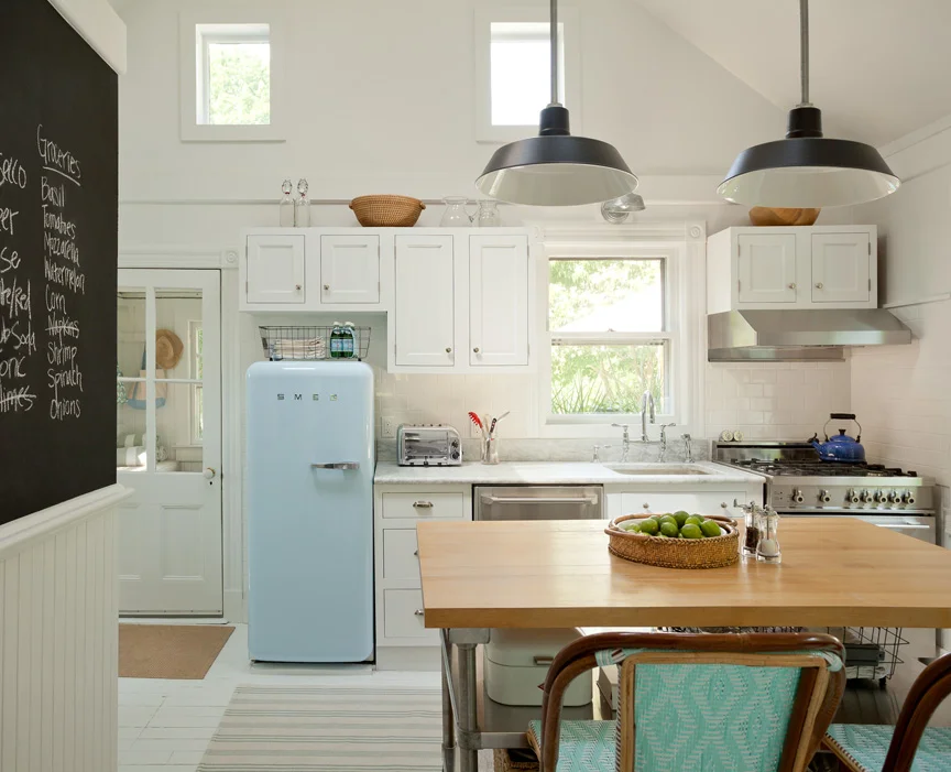 The vintage -looking powder blue Smeg refrigerator and the built-in chalkboard make the kitchen feel playful and casual, the perfect family gathering spot.