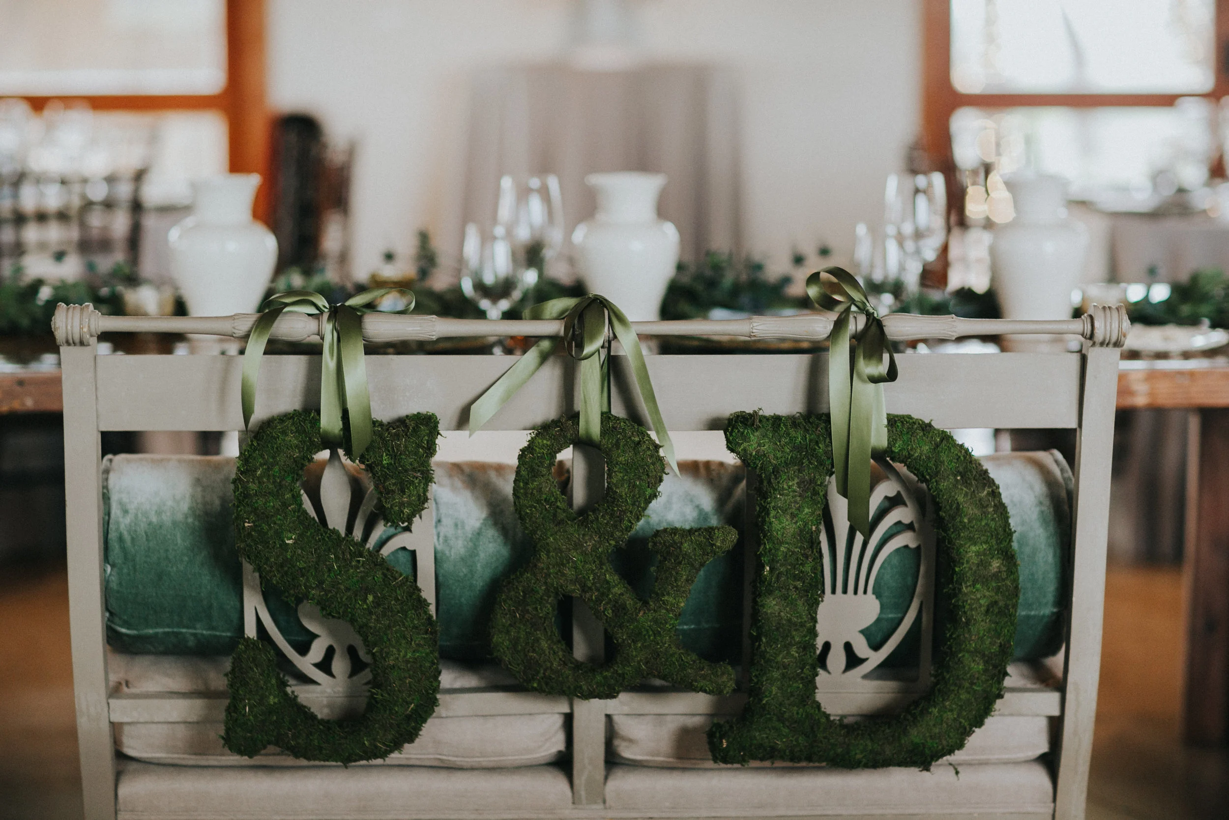 We used my parents' antique settee at the head table for myself and David, and decorated it with moss "S" and "D" letters, to echo the moss chargers.&nbsp;
