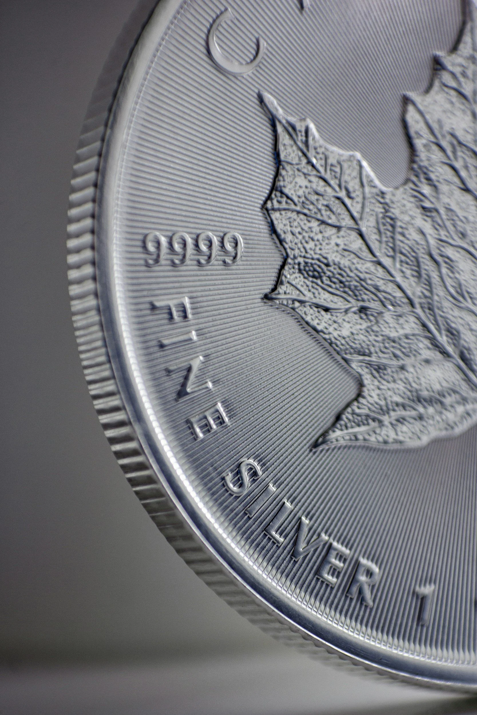 Close-up of a Canadian quarter coin showing a maple leaf and the words 'THE 1999 SILVER'.