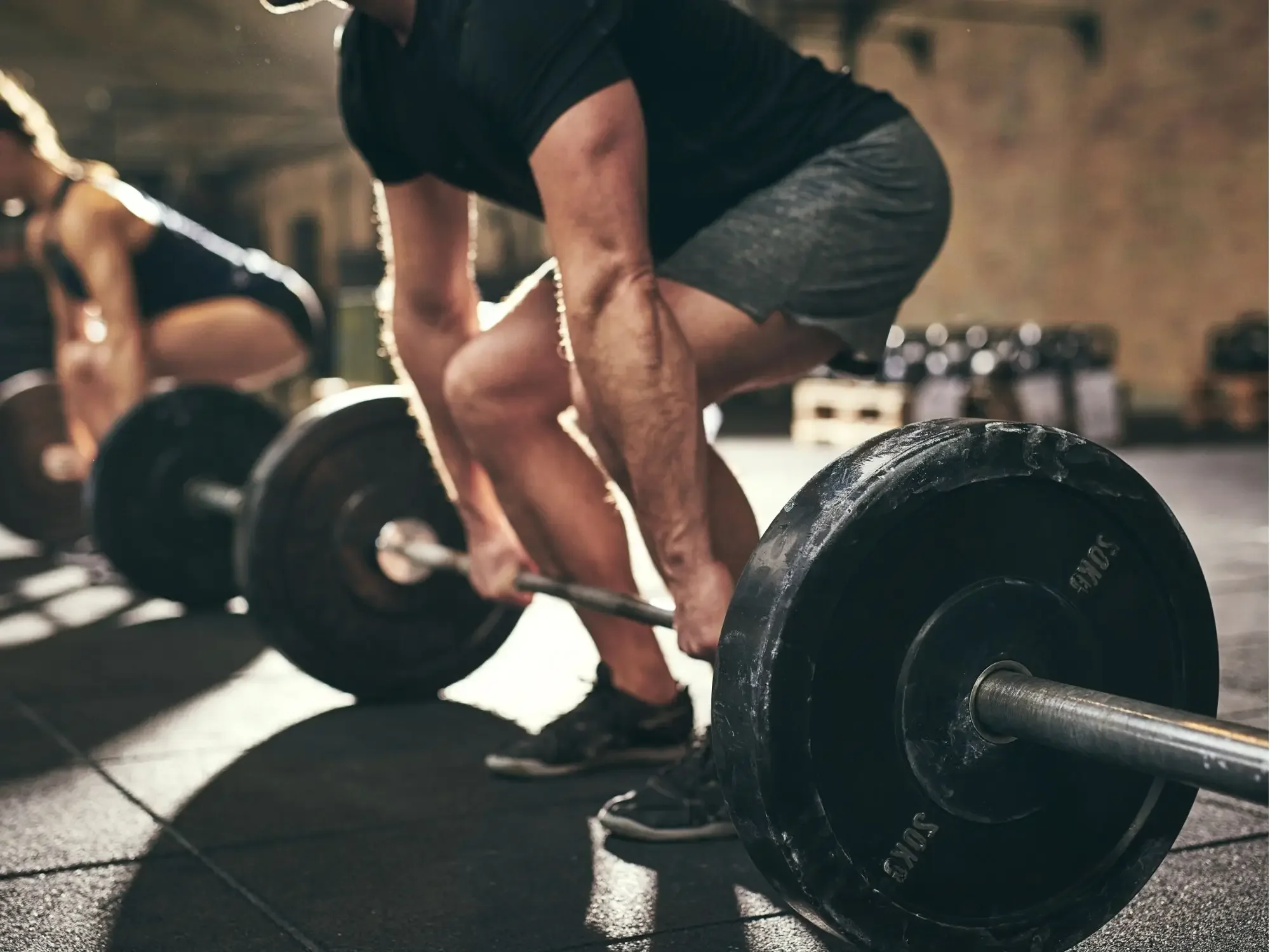 A person lifting a heavy barbell in a gym, in a deadlift position, focusing on their workout.