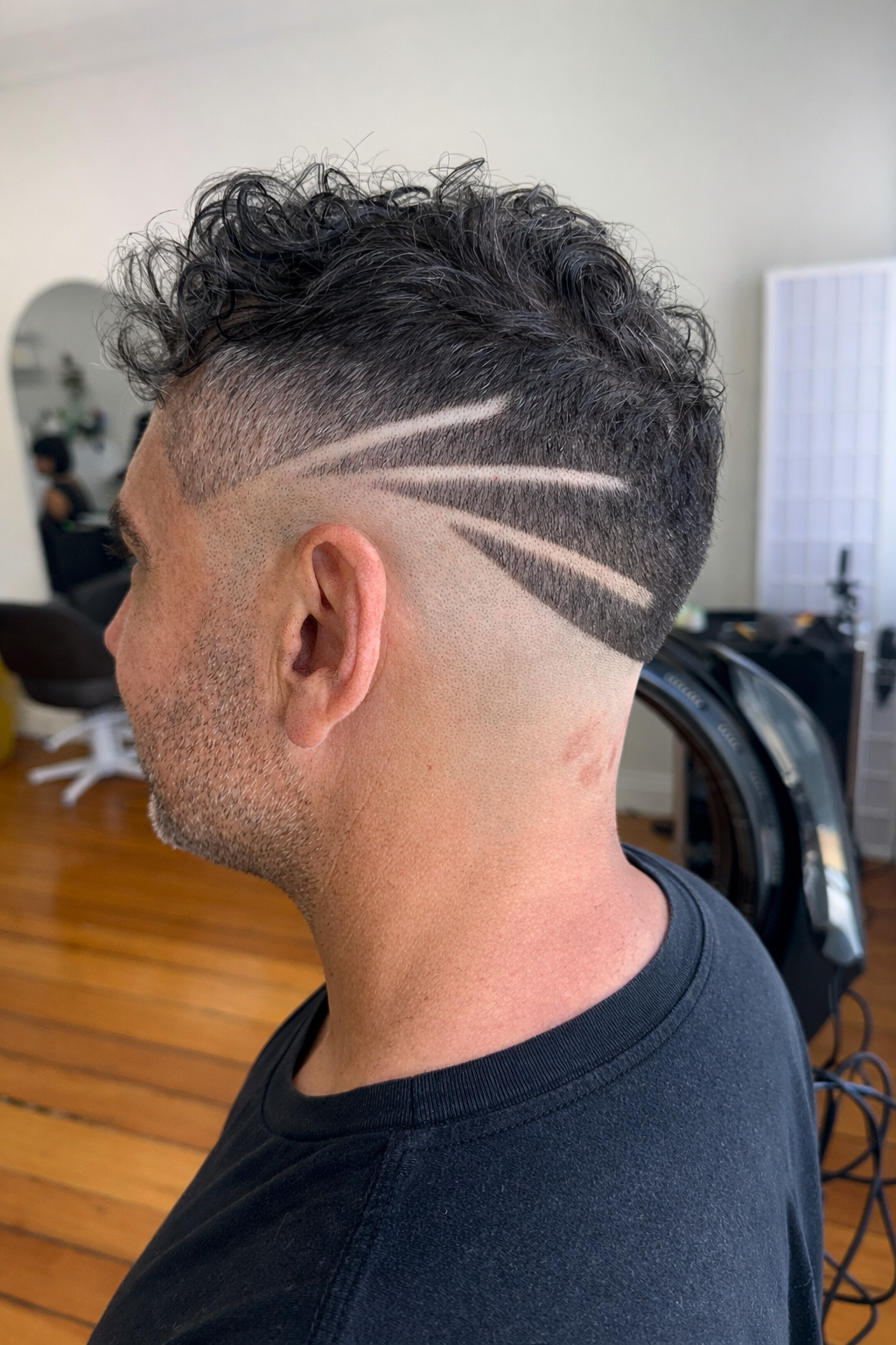 Side view of a man with a modern haircut featuring a fade and artistic shaved lines on the side of his head.