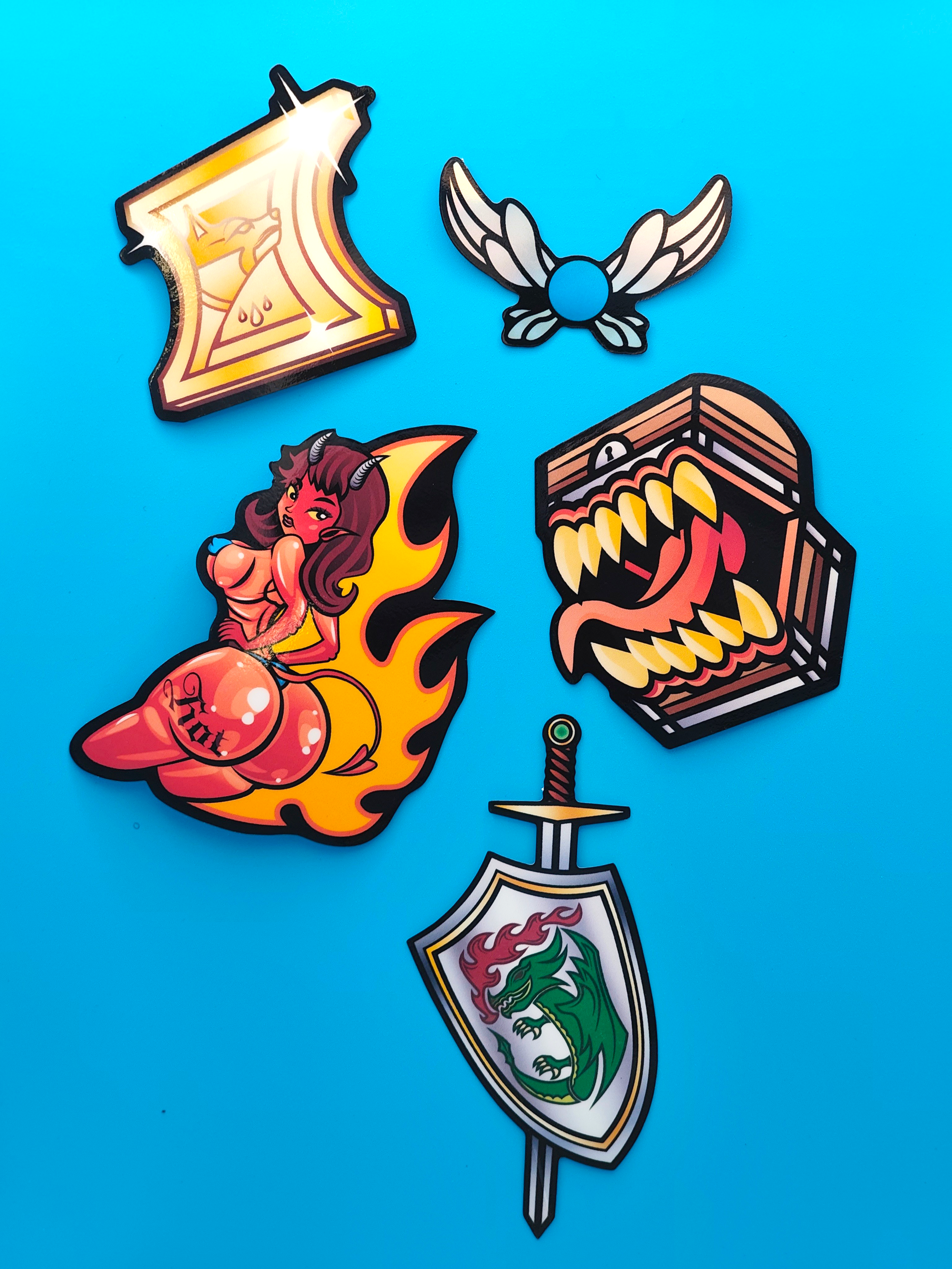 Set of five colorful patches on a blue background, including a yellow axe with a dragon logo, a black and white insect with wings, a cartoonish female devil with horns and a tail, a fiery dragon's head inside an open treasure chest, and a shield with