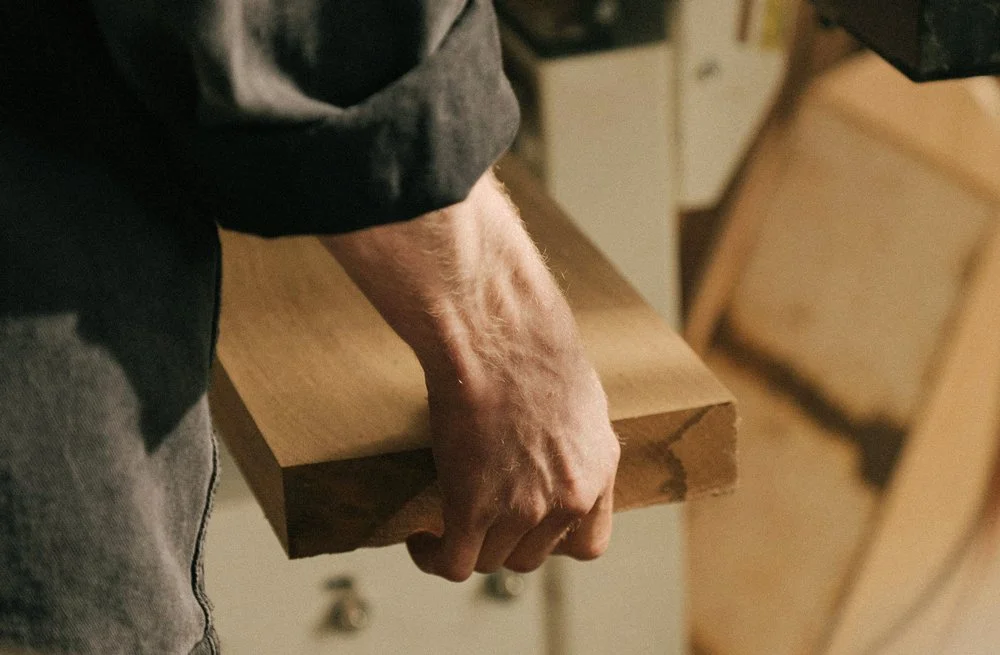 Nahaufnahme einer Hand, die ein Brett hält, wahrscheinlich in einer Werkstatt.