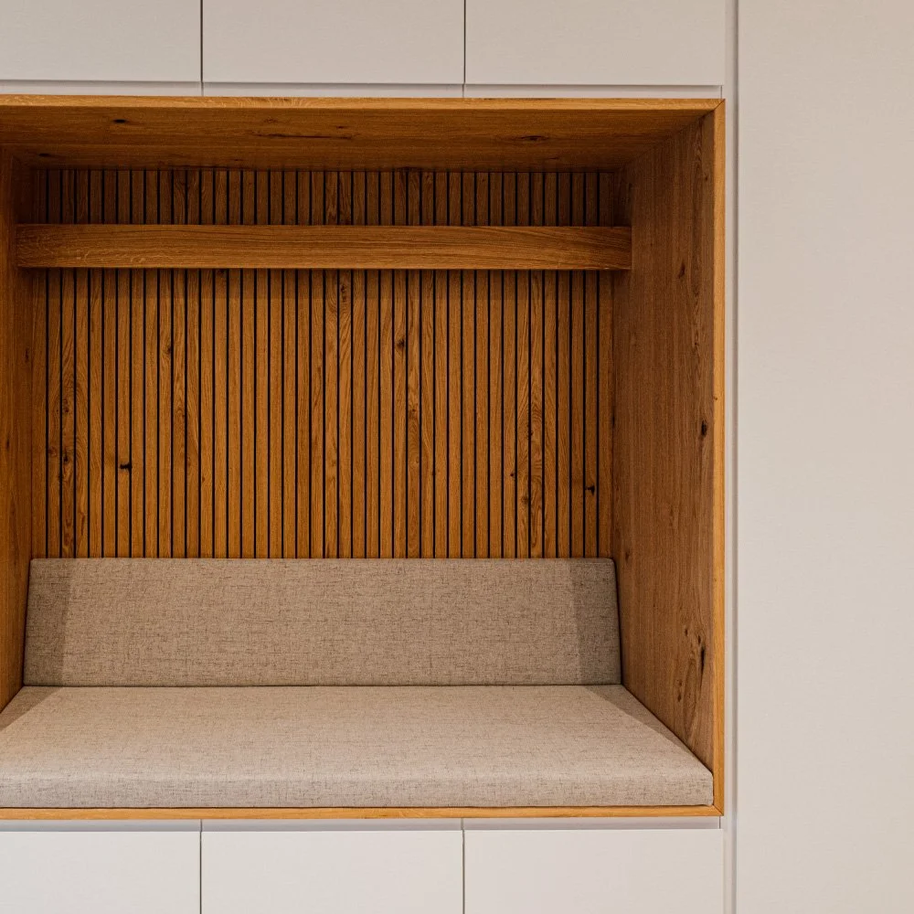 Innenansicht einer Sitznische mit Holzwand und beige Kissen.