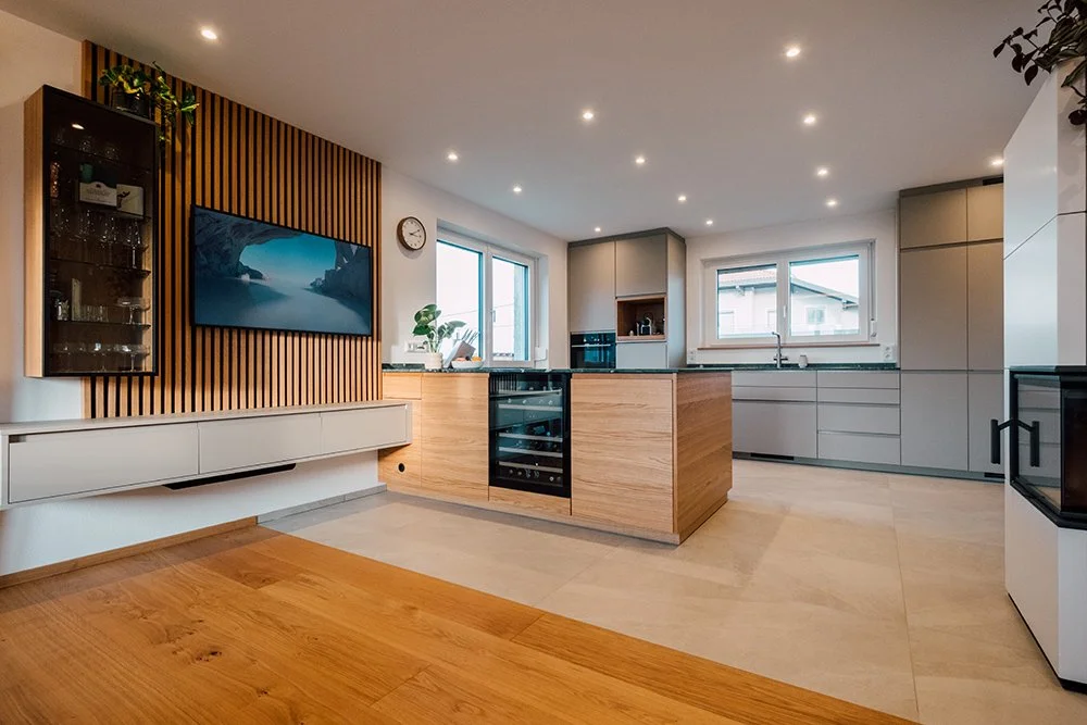 Ein Holztisch mit bunten Polsterstühlen in einem modernen Raum, dekoriert mit Blumen und kleinen Gegenständen.