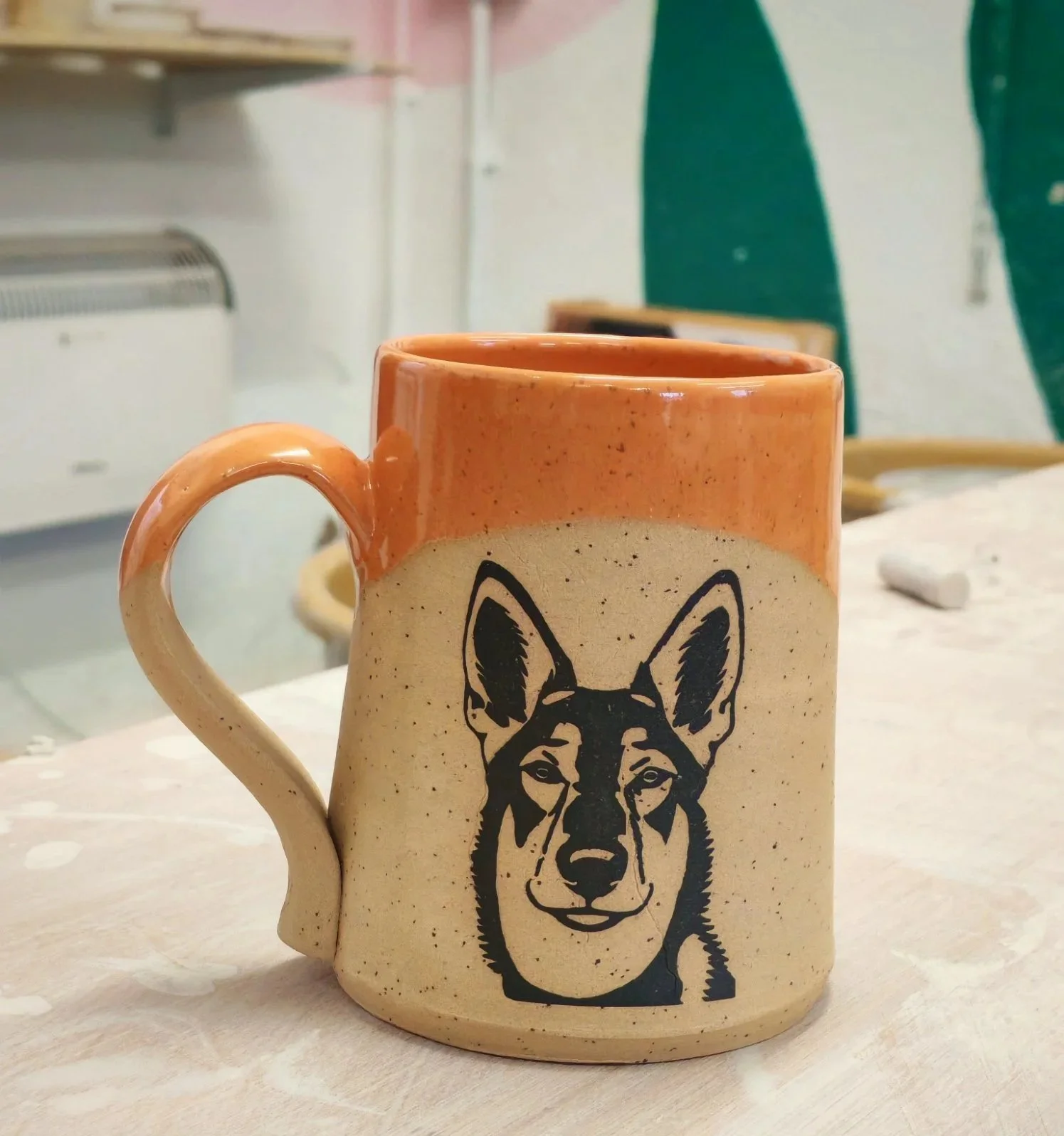 Ceramic mug with a dog's face illustration on it, placed on a light-colored table.