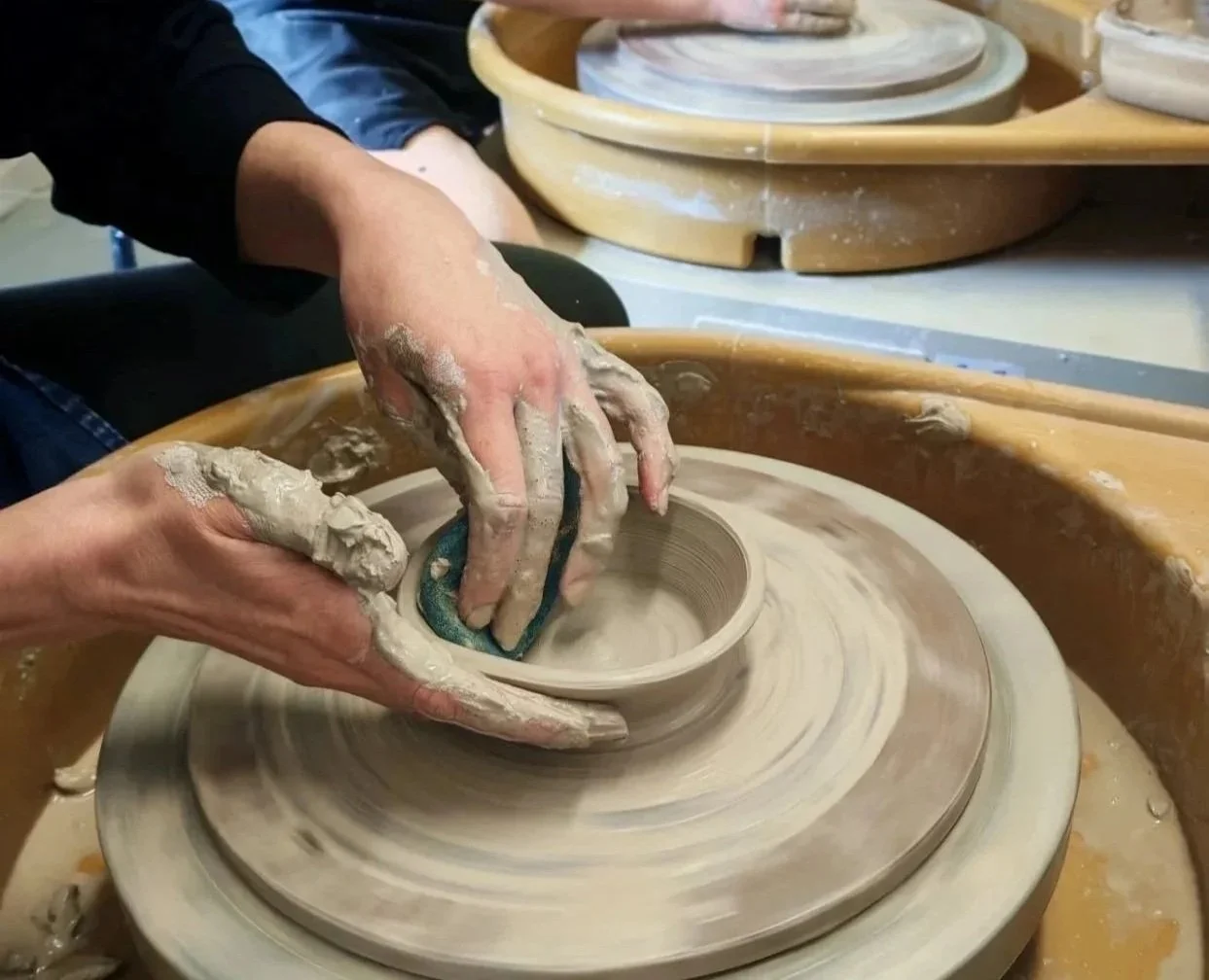 Person shaping clay on a pottery wheel in a pottery studio.