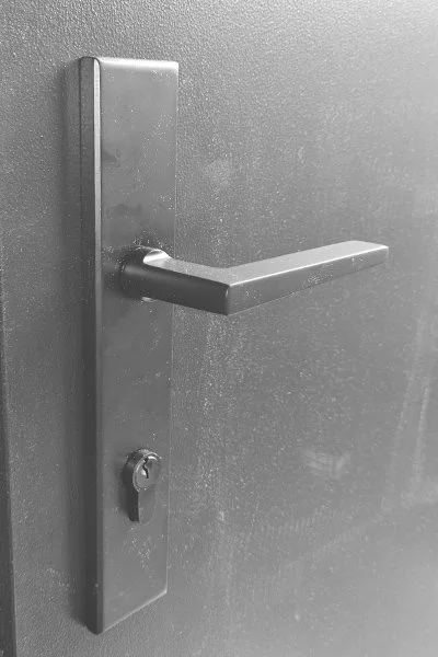 Close-up of a metal door handle and keyhole on a gray door.