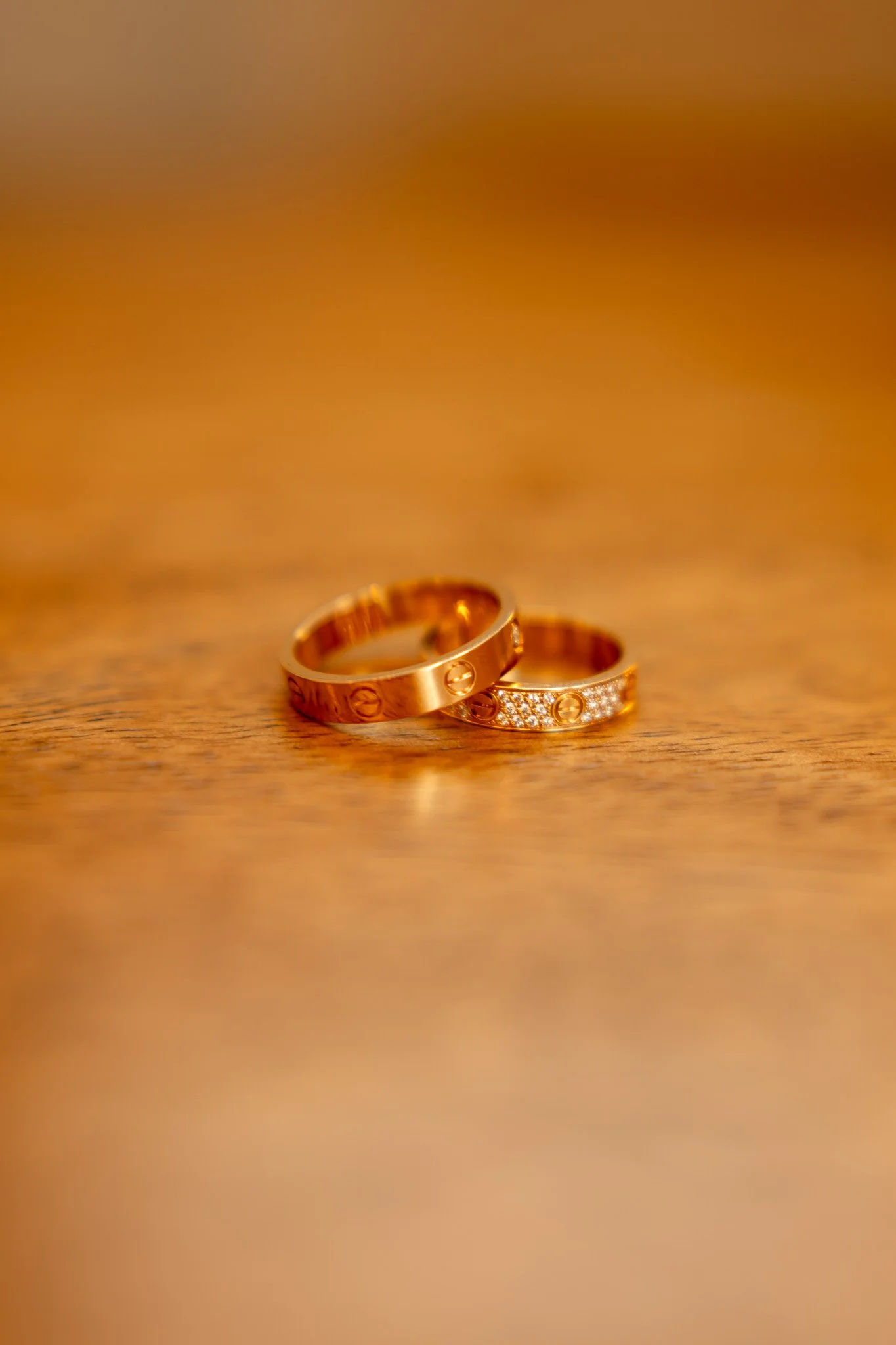 Two gold rings resting on a wooden surface, one with embedded diamonds.