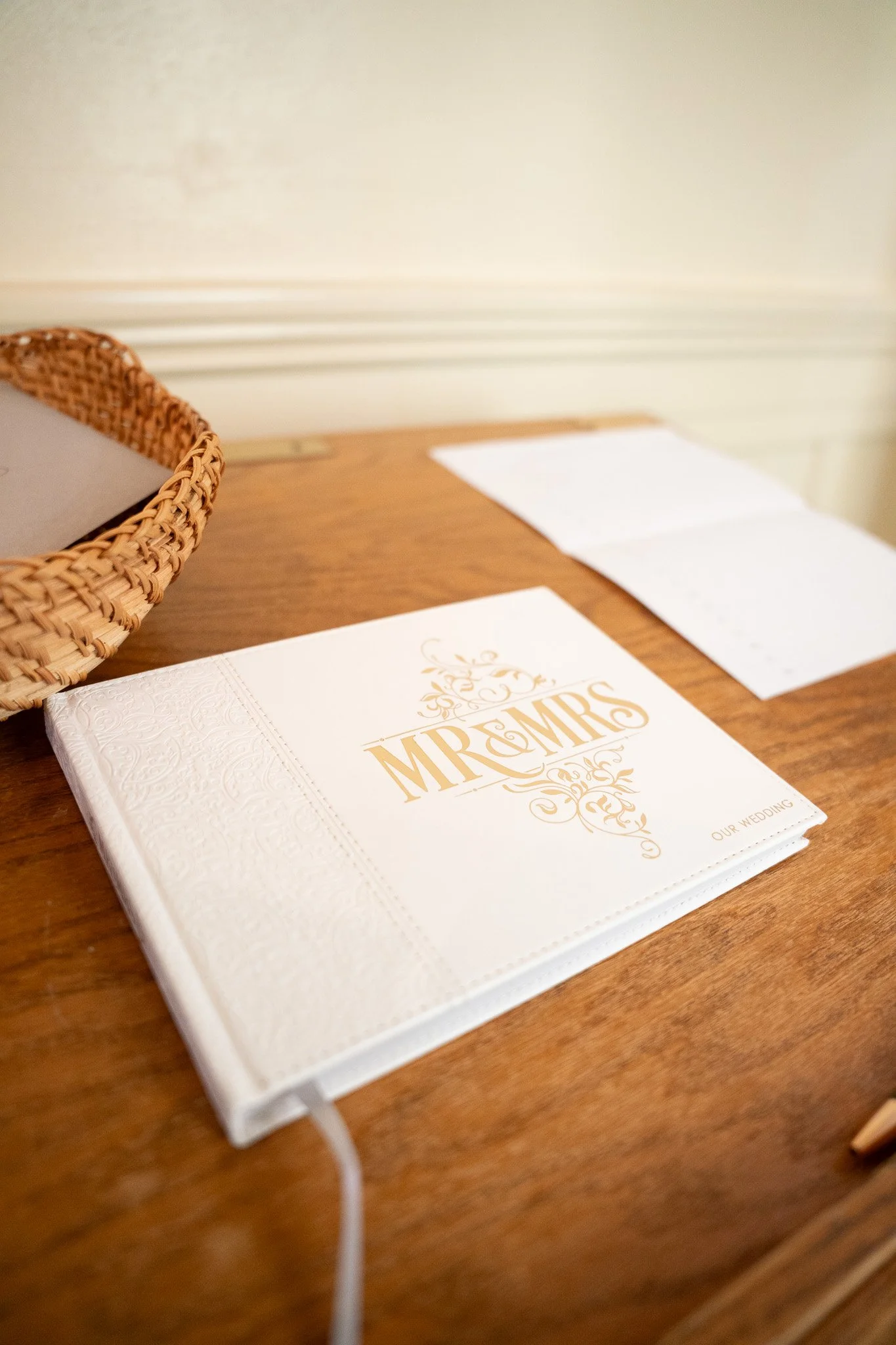 Wedding photo album titled 'Mr & Mrs' on a wooden table with a white lace cover and gold lettering.